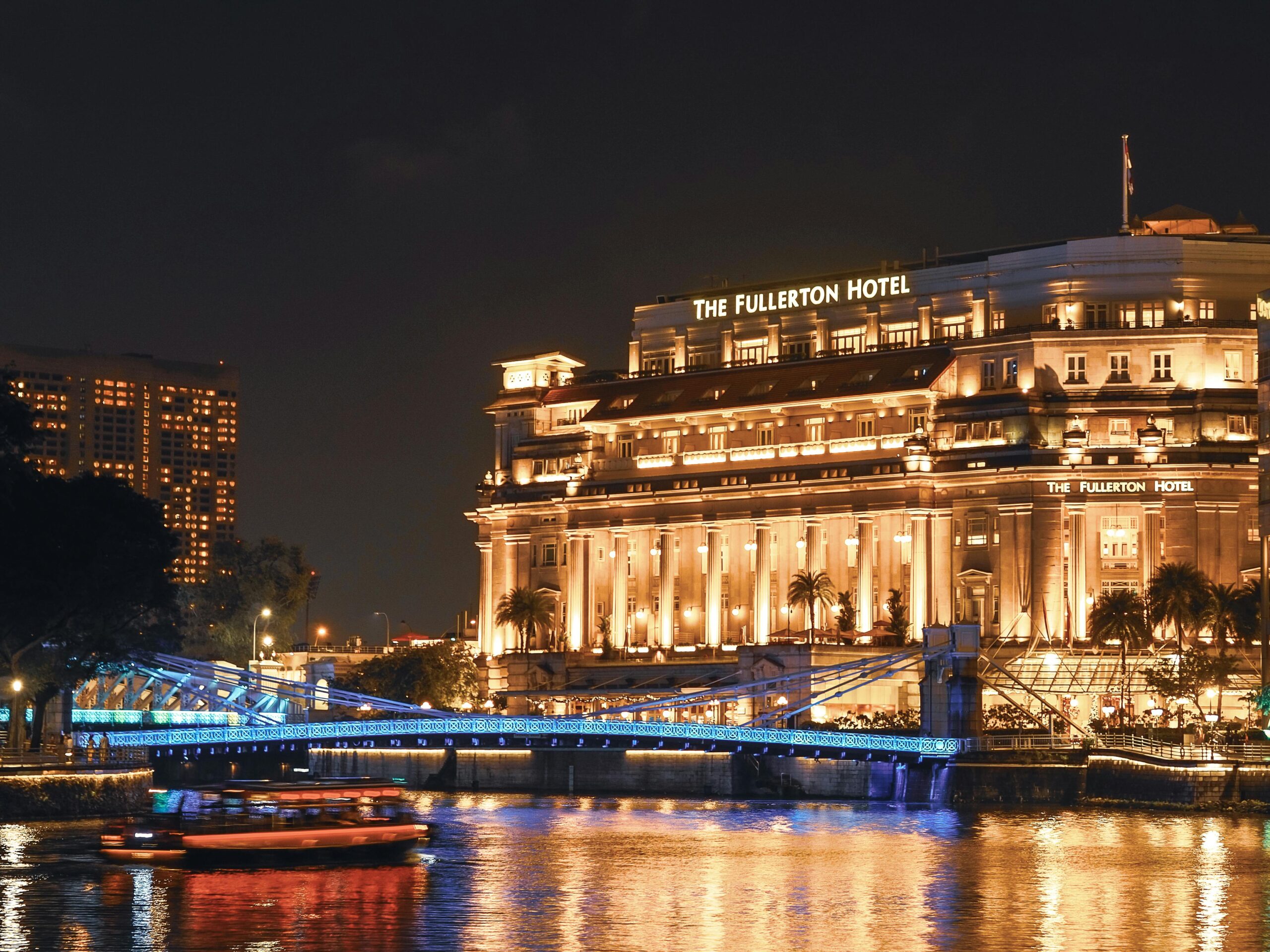 Stunning nighttime view of The Fullerton Hotel in Singapore, beautifully illuminated along the waterfront.