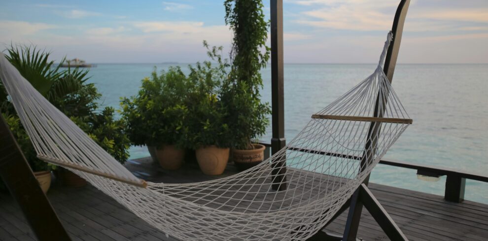 Relax in a hammock with a peaceful ocean view, surrounded by lush greenery, in a tropical setting.