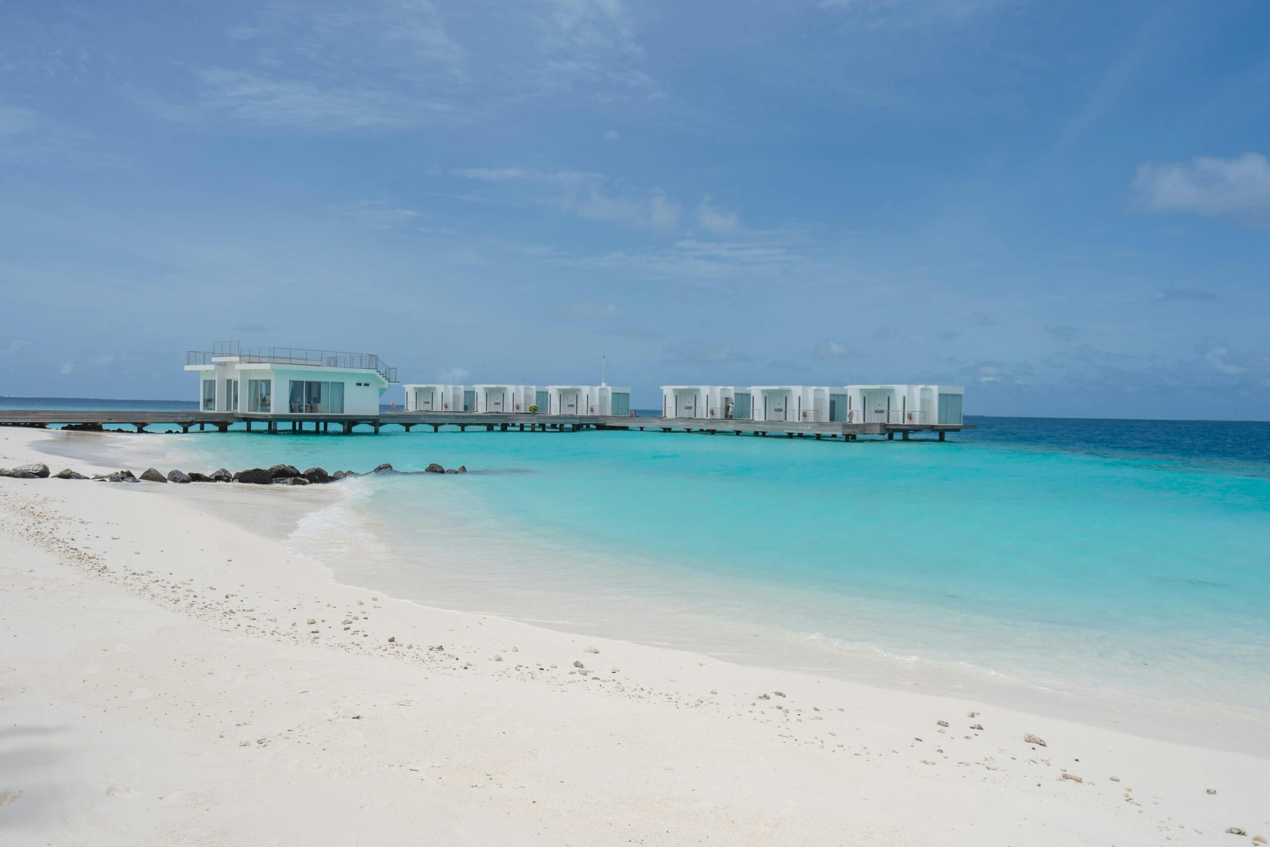 Luxurious overwater villas on a pristine beach with turquoise waters and clear blue skies.