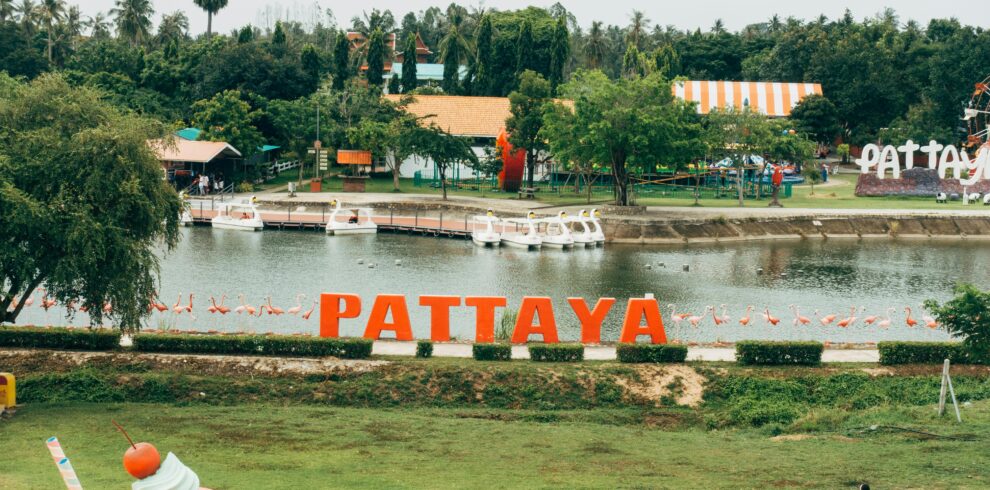 A vibrant scene in Pattaya, Thailand with a lake, iconic sign, and colorful decorations.