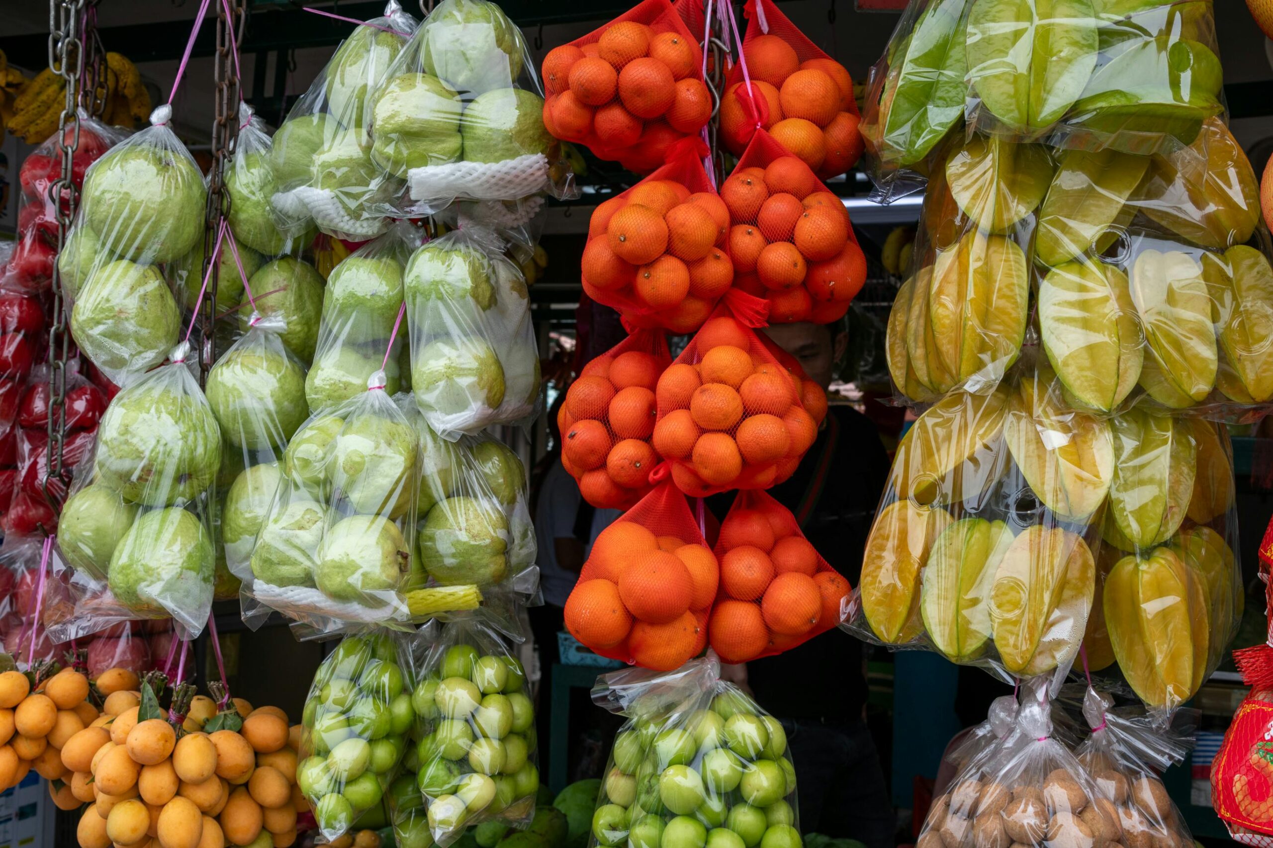 Fresh tropical fruits displayed in plastic bags at a local Melaka market.