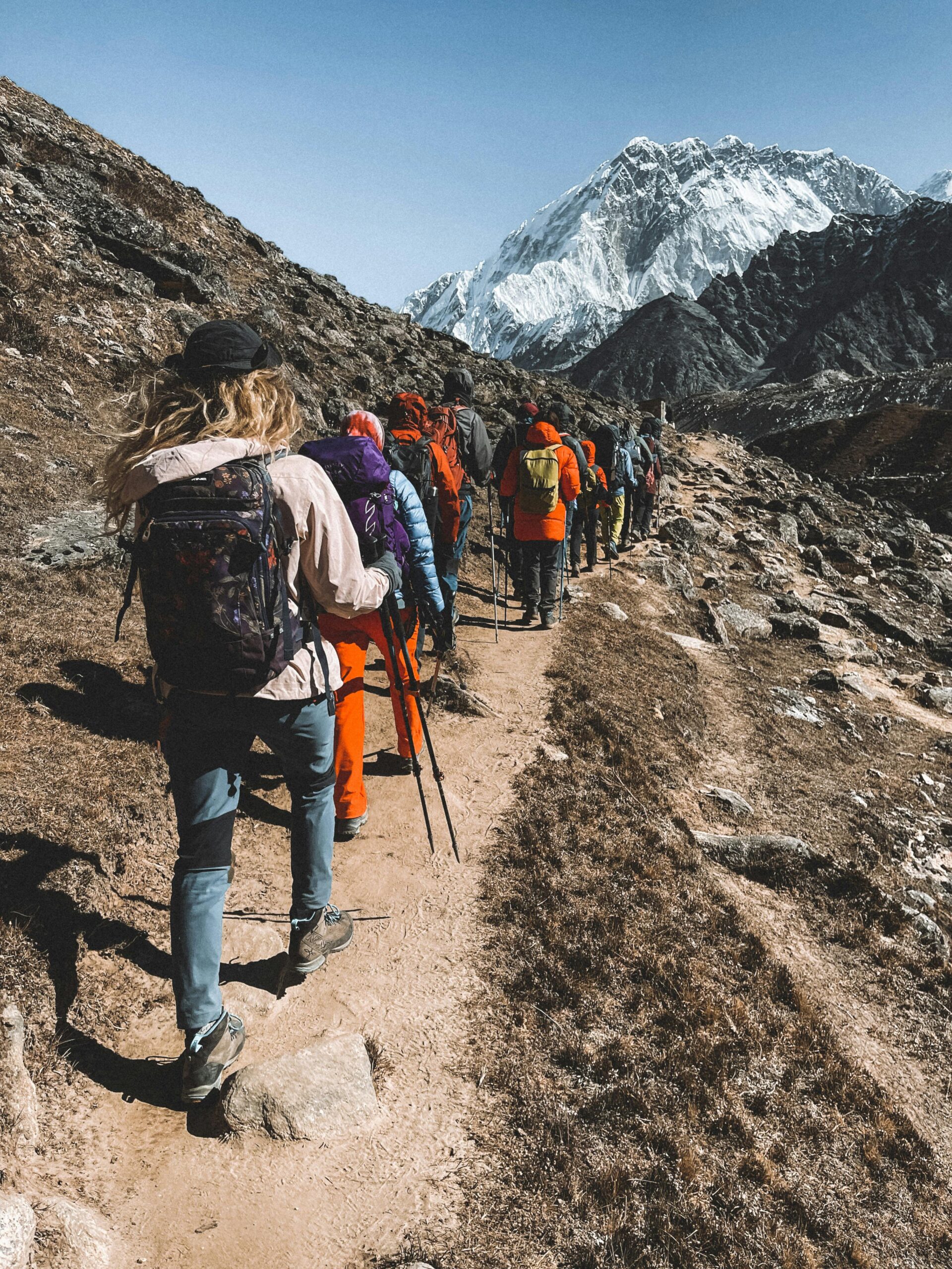 Adventurous group of hikers trekking on a scenic mountain trail in Nepal, surrounded by stunning landscapes.