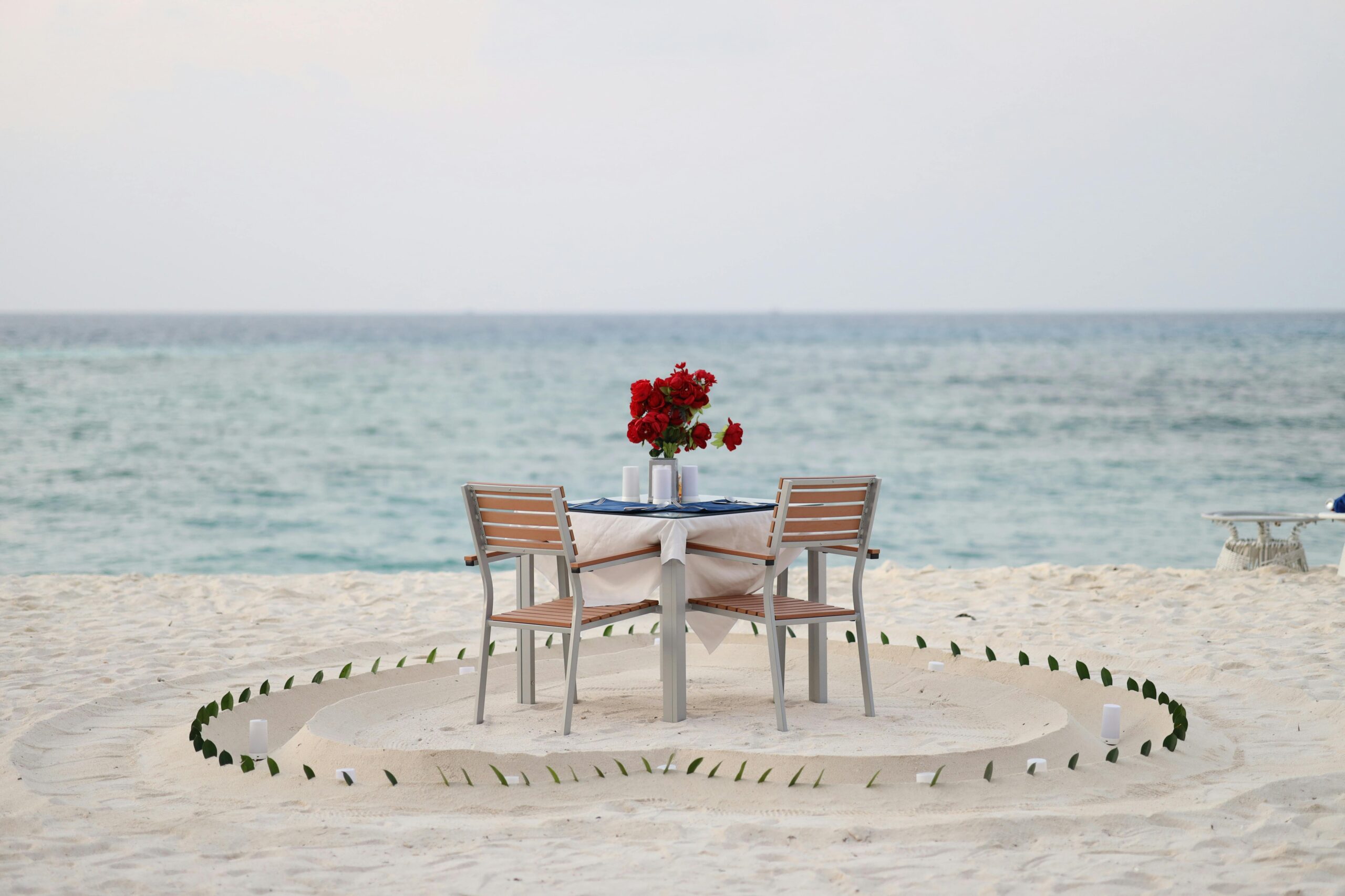 Romantic dinner setup on a serene Maldivian beach with ocean view, perfect for couples.