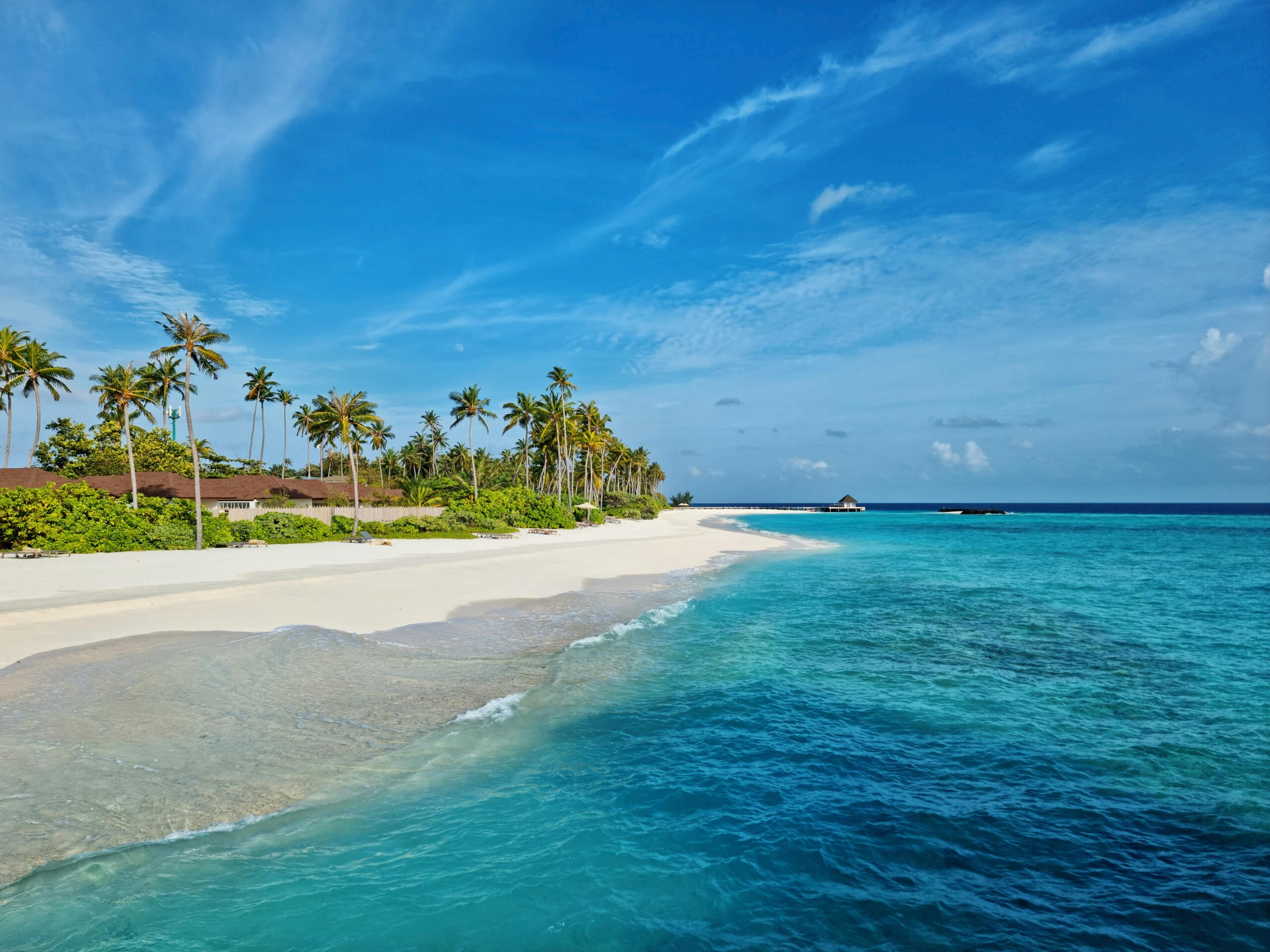 Experience the serene beauty of Maldives with turquoise waters and white sandy beach under a clear blue sky.
