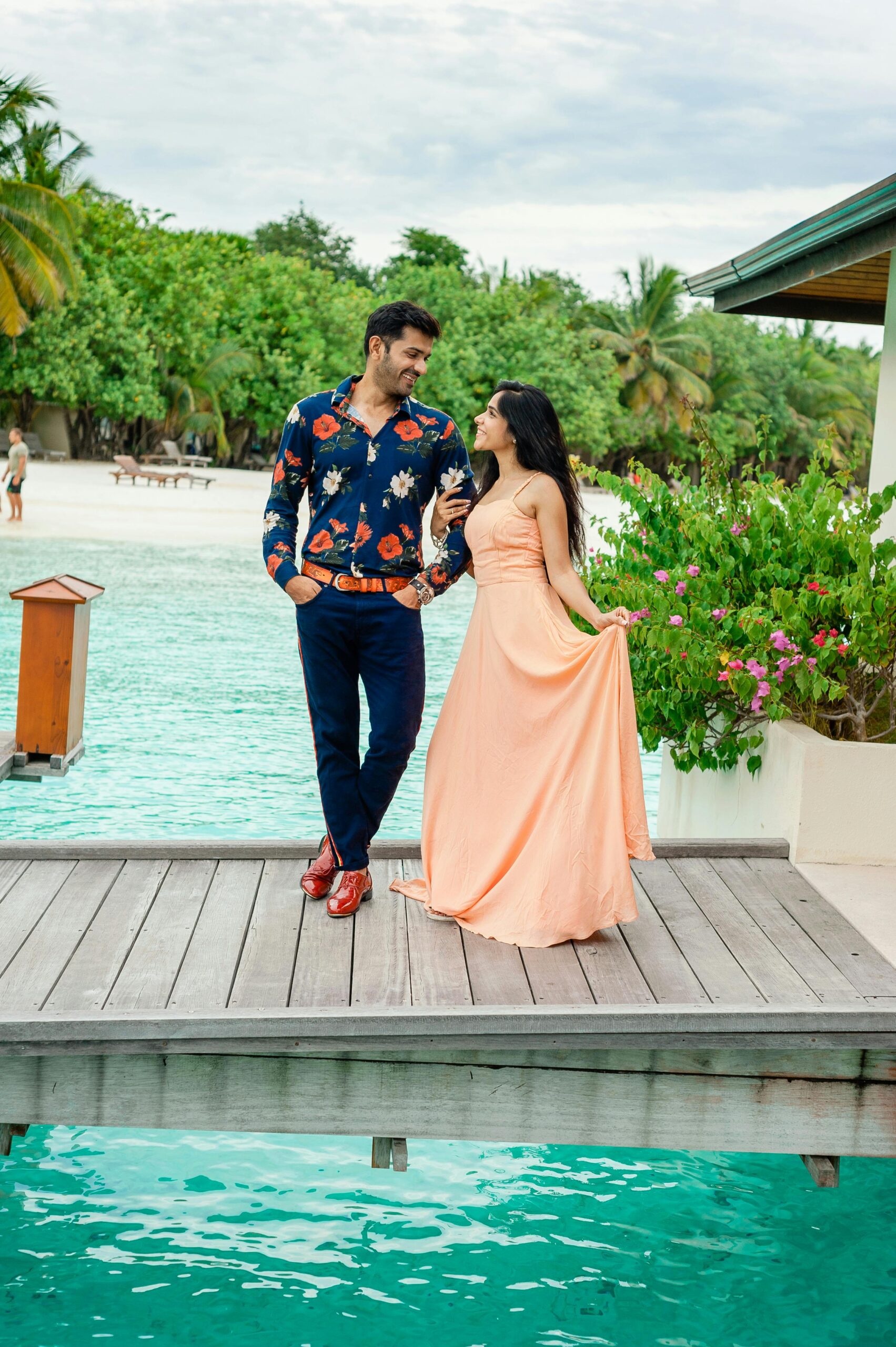 Couple enjoying a stylish photoshoot on a dock in the Maldives, showcasing resort fashion and romantic vibes.