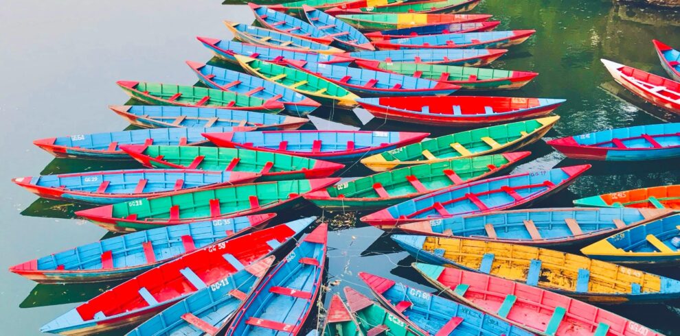 Colorful boats create a stunning pattern on Phewa Lake, Pokhara, capturing Nepal's vibrant culture and serene landscape.