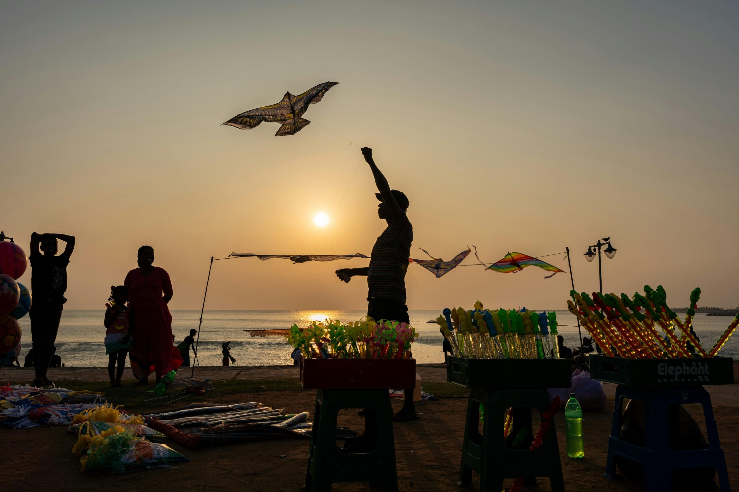 People enjoy kite flying on Colombo's seaside during sunset, creating a vibrant coastal scene.