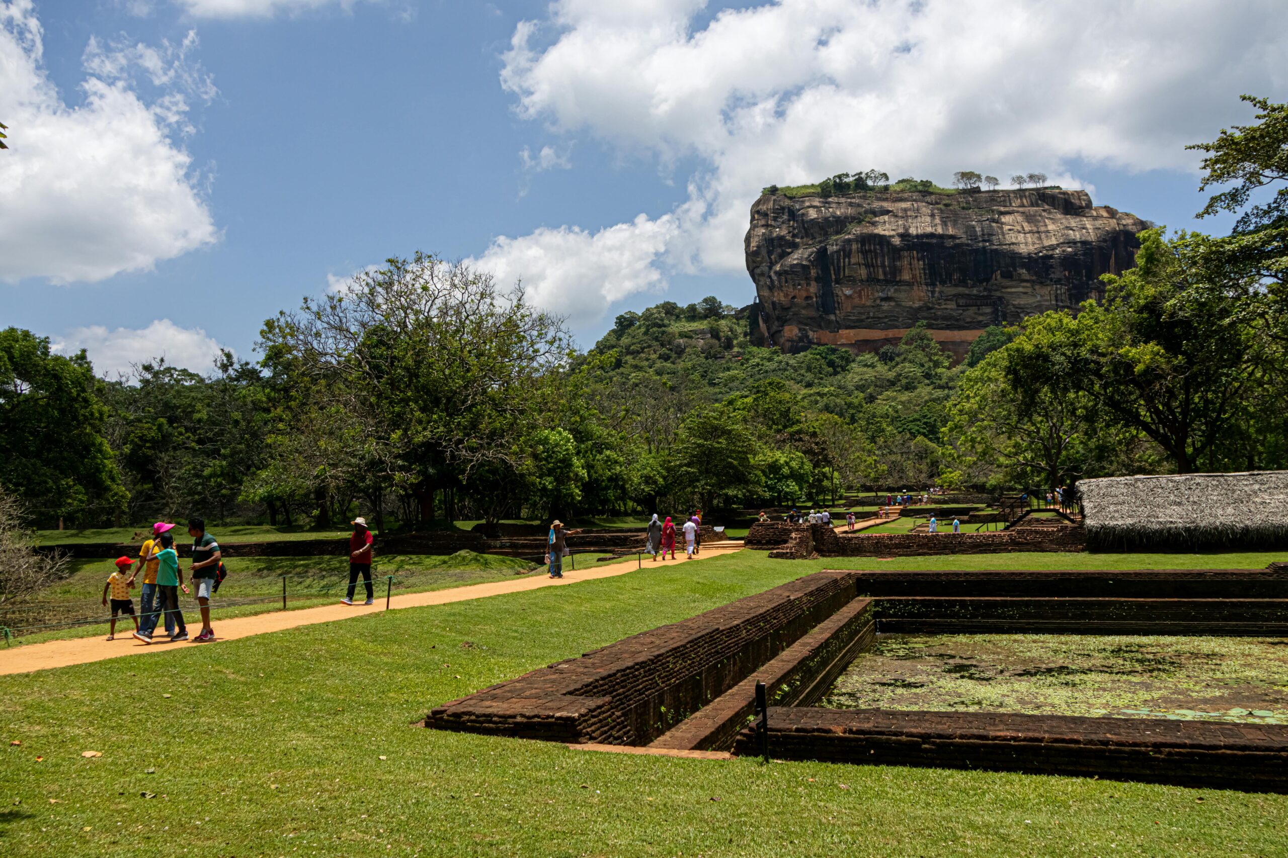 A scenic view of Sigiriya Rock Fortress surrounded by lush greenery and visitors.