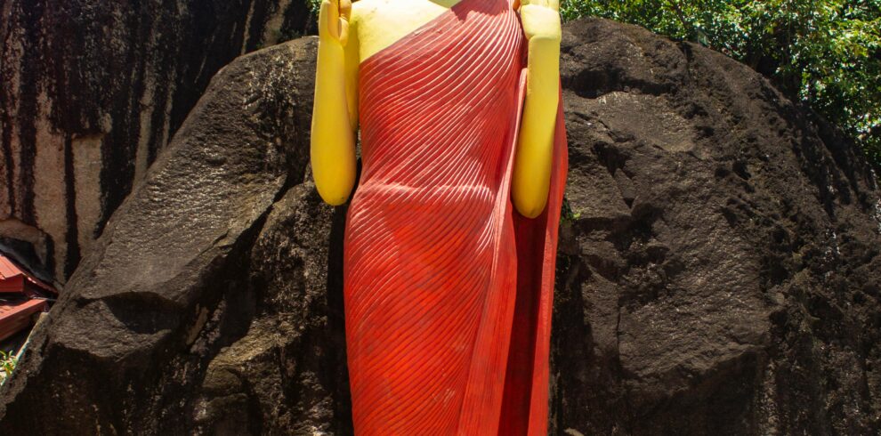 Striking Buddha statue against rocky backdrop in Unawatuna, Sri Lanka.