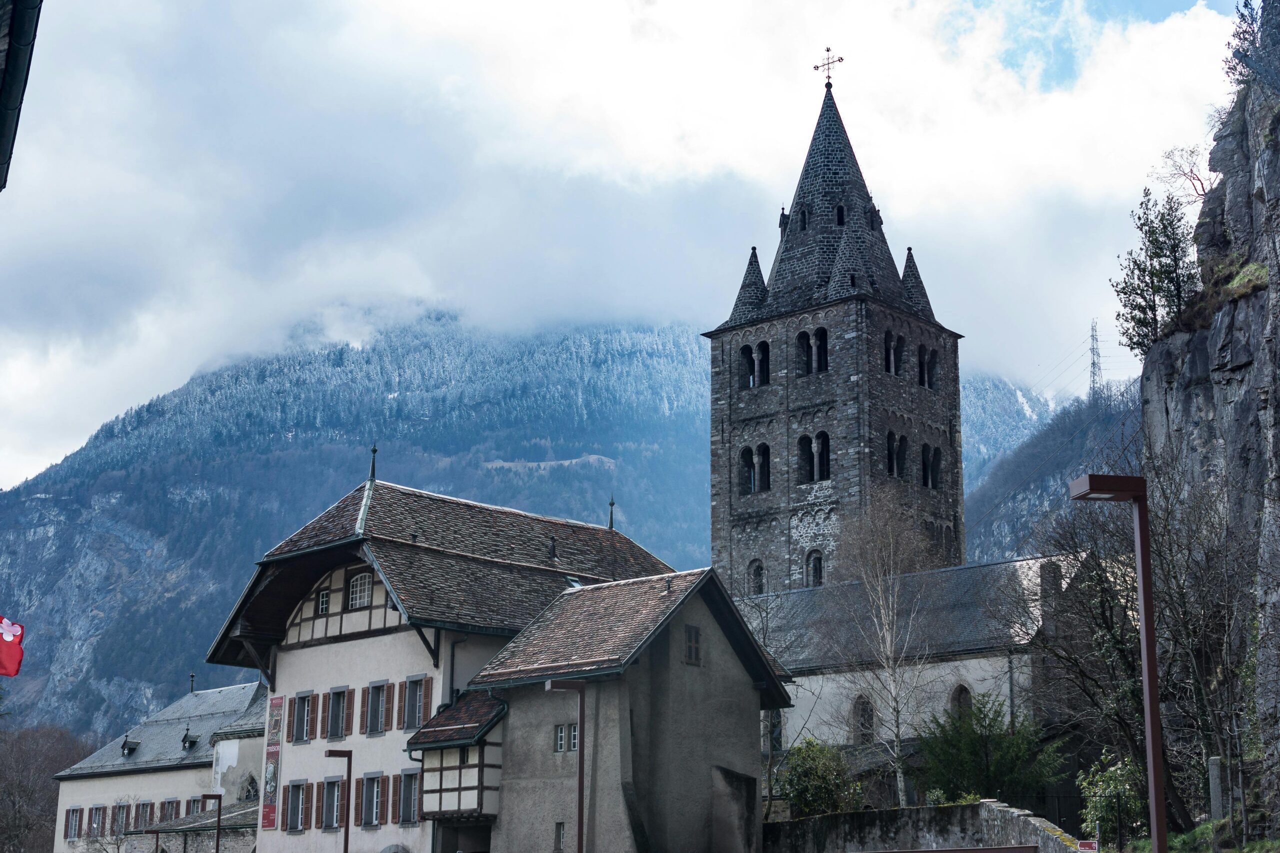 Scenic view of a historic church and tower amidst the mountains in Saint-Maurice, Switzerland.