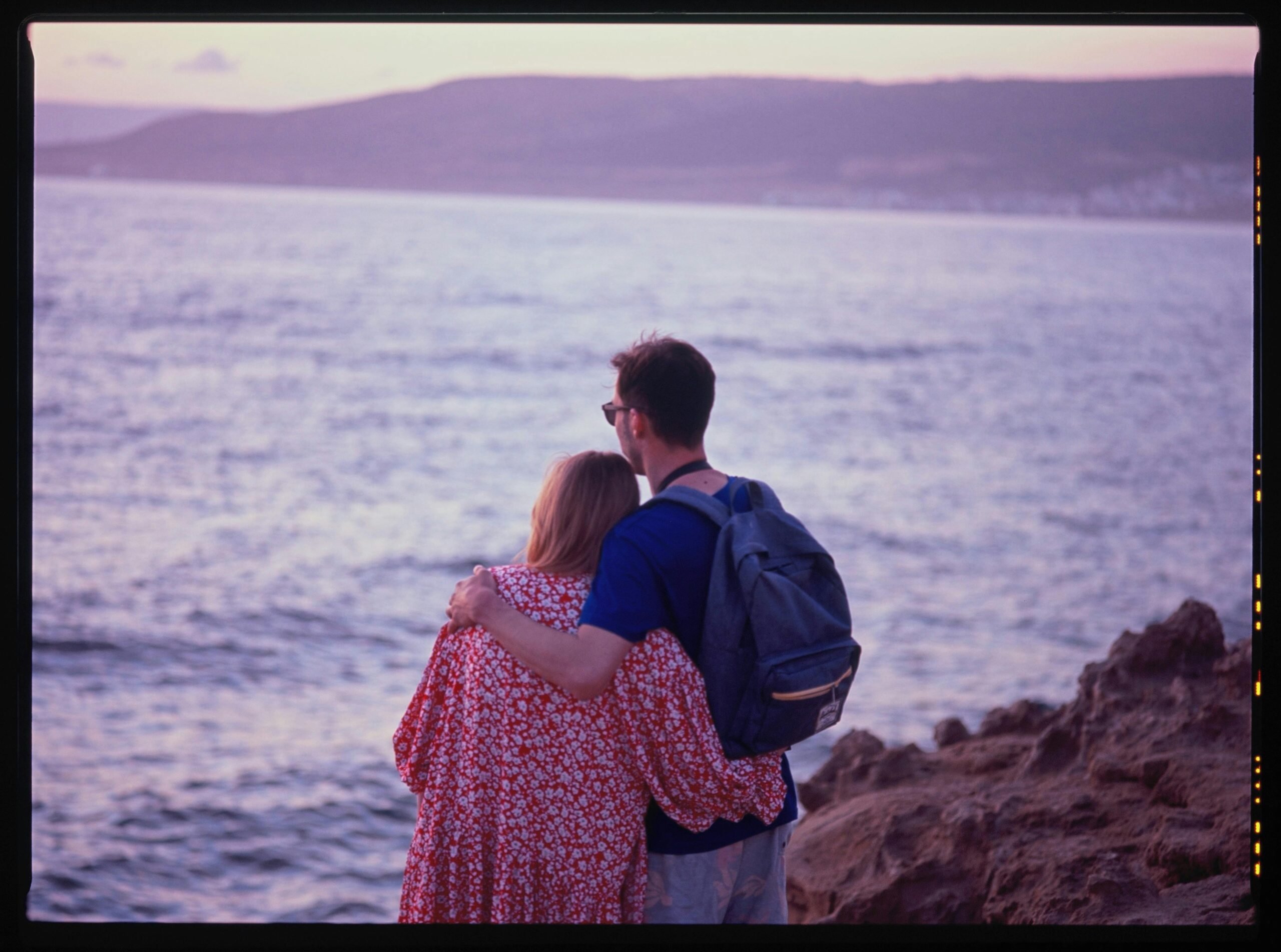 A couple enjoying a romantic embrace by the sea in Morocco at sunset.