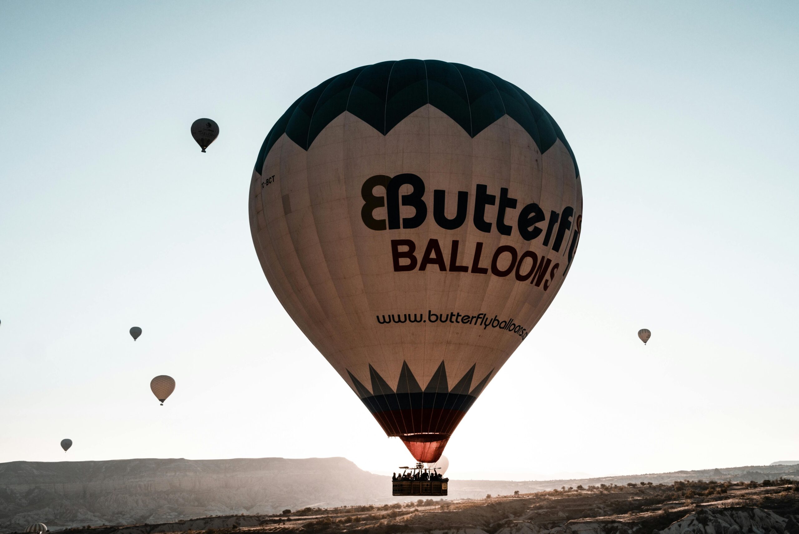 A breathtaking view of hot air balloons flying over Cappadocia, Türkiye at sunrise.