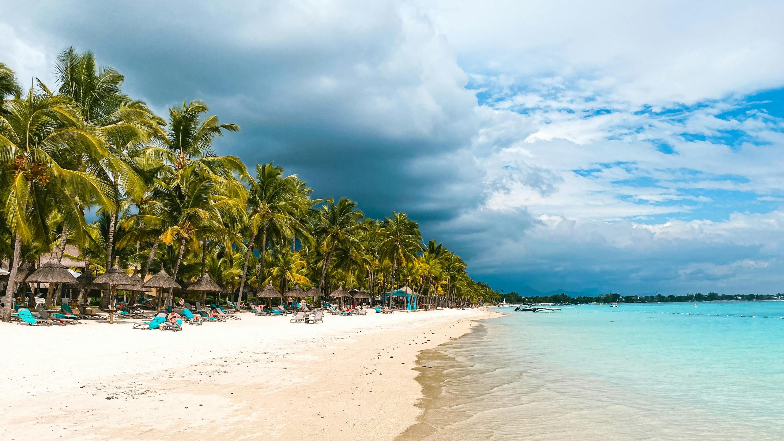 Peaceful tropical beach at Trou-aux-Biches with palm trees and clear waters under a cloudy sky.