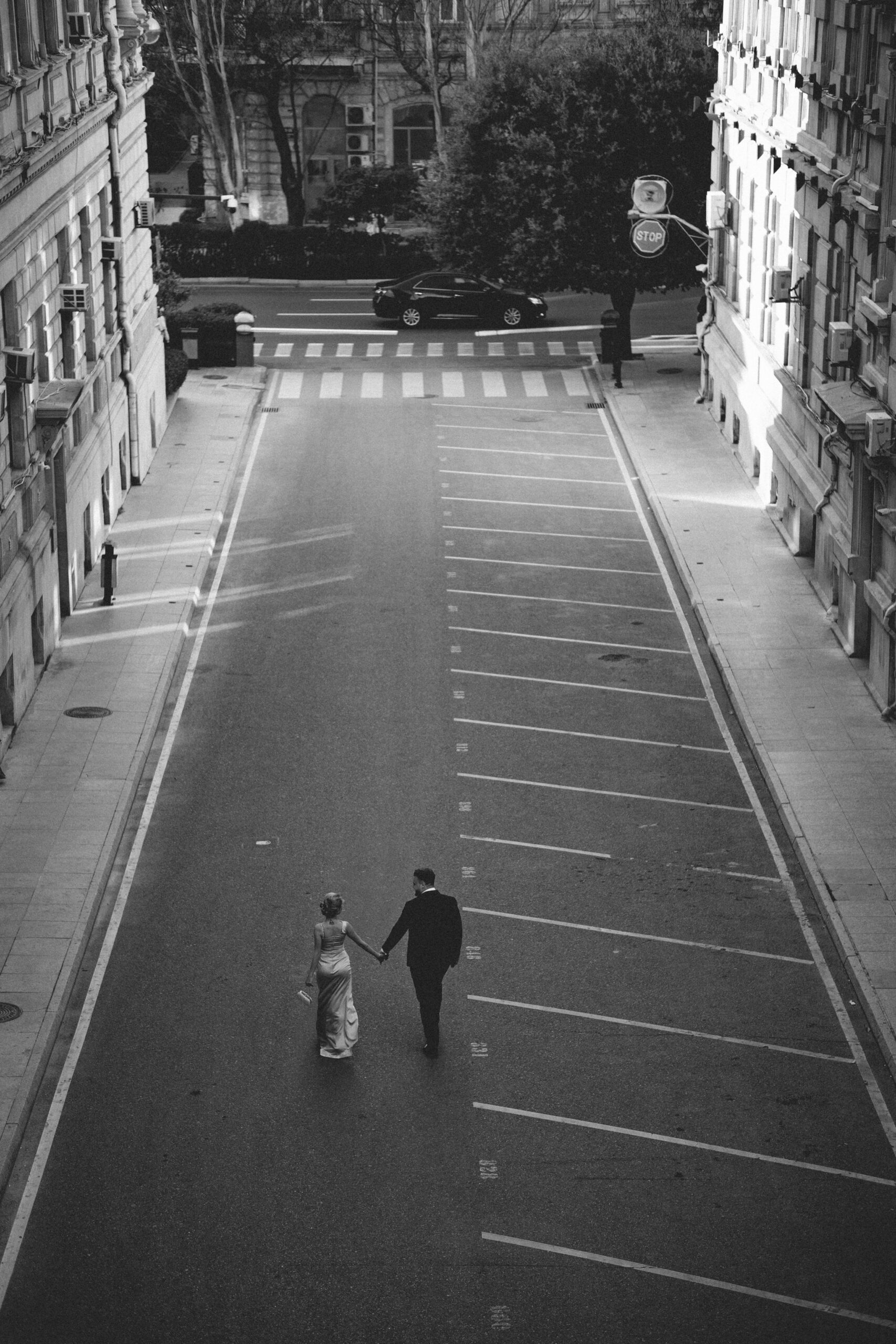 Black and white photo of a couple walking on a city street, holding hands.
