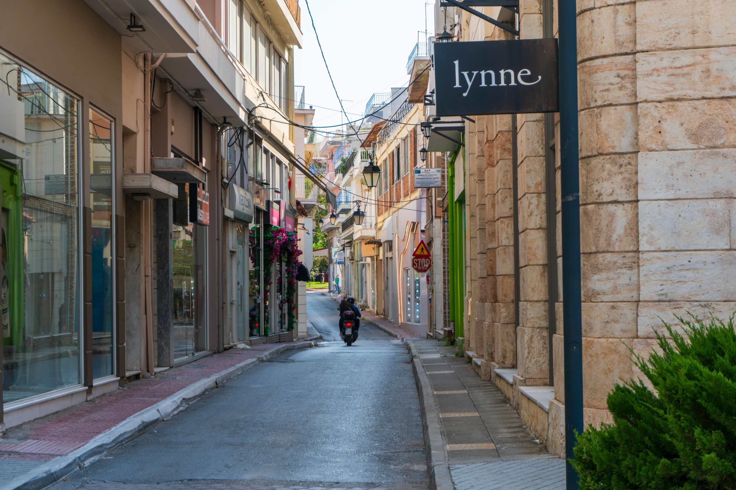 A picturesque narrow street lined with shops and a motorcyclist in an urban setting.