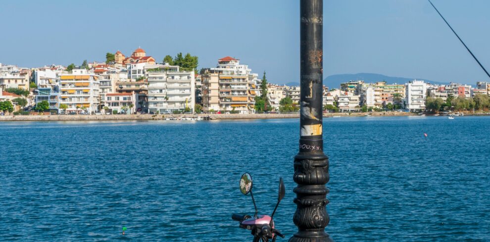 A colorful scooter parked by a scenic seaside promenade under a clear blue sky.