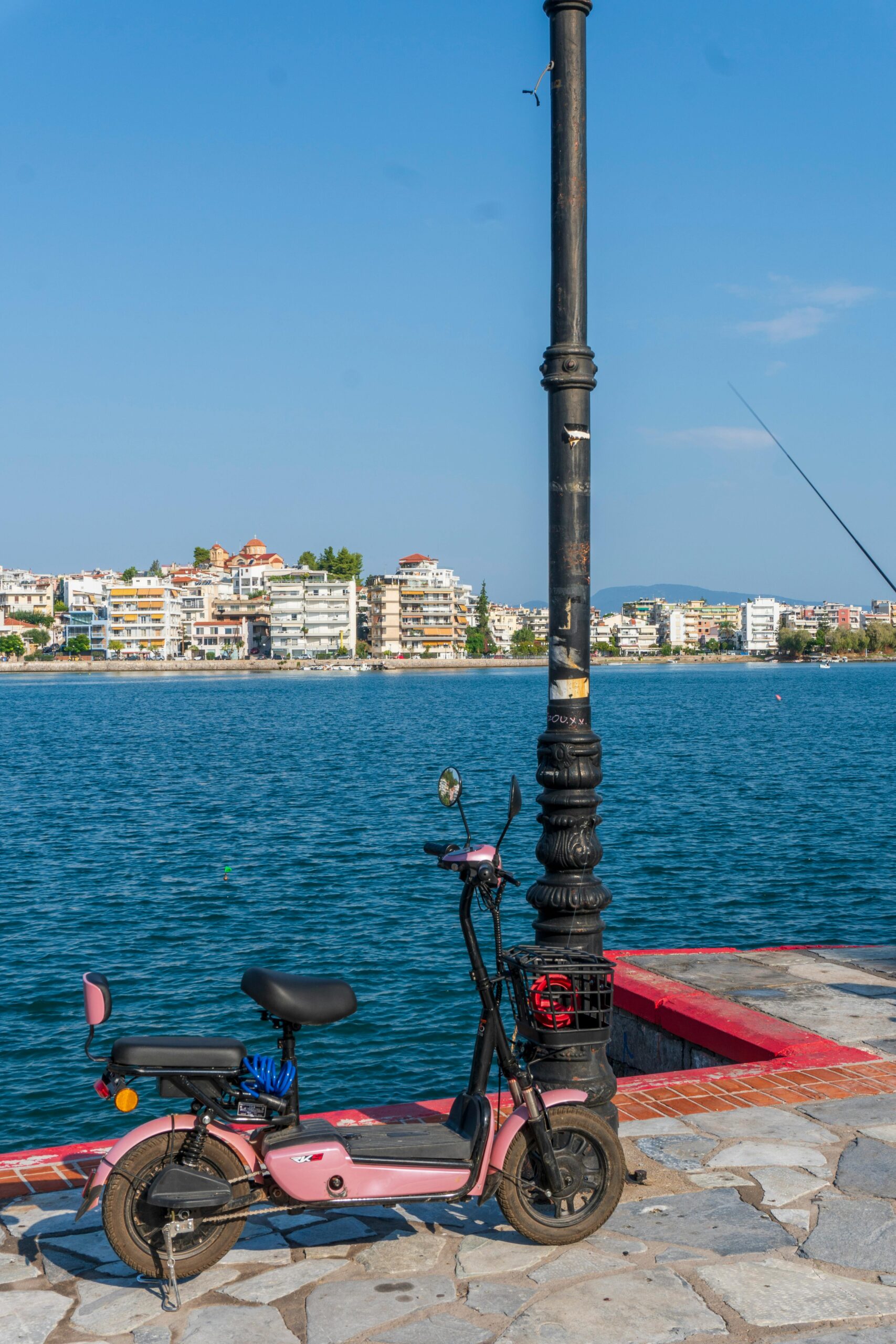A colorful scooter parked by a scenic seaside promenade under a clear blue sky.