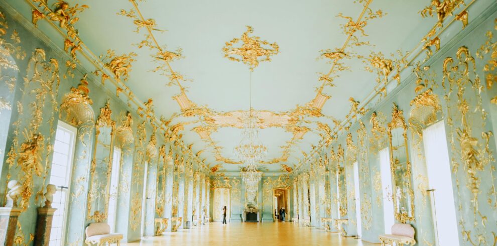 Luxurious Baroque-style room with intricate gold detailing and elegant chandeliers.