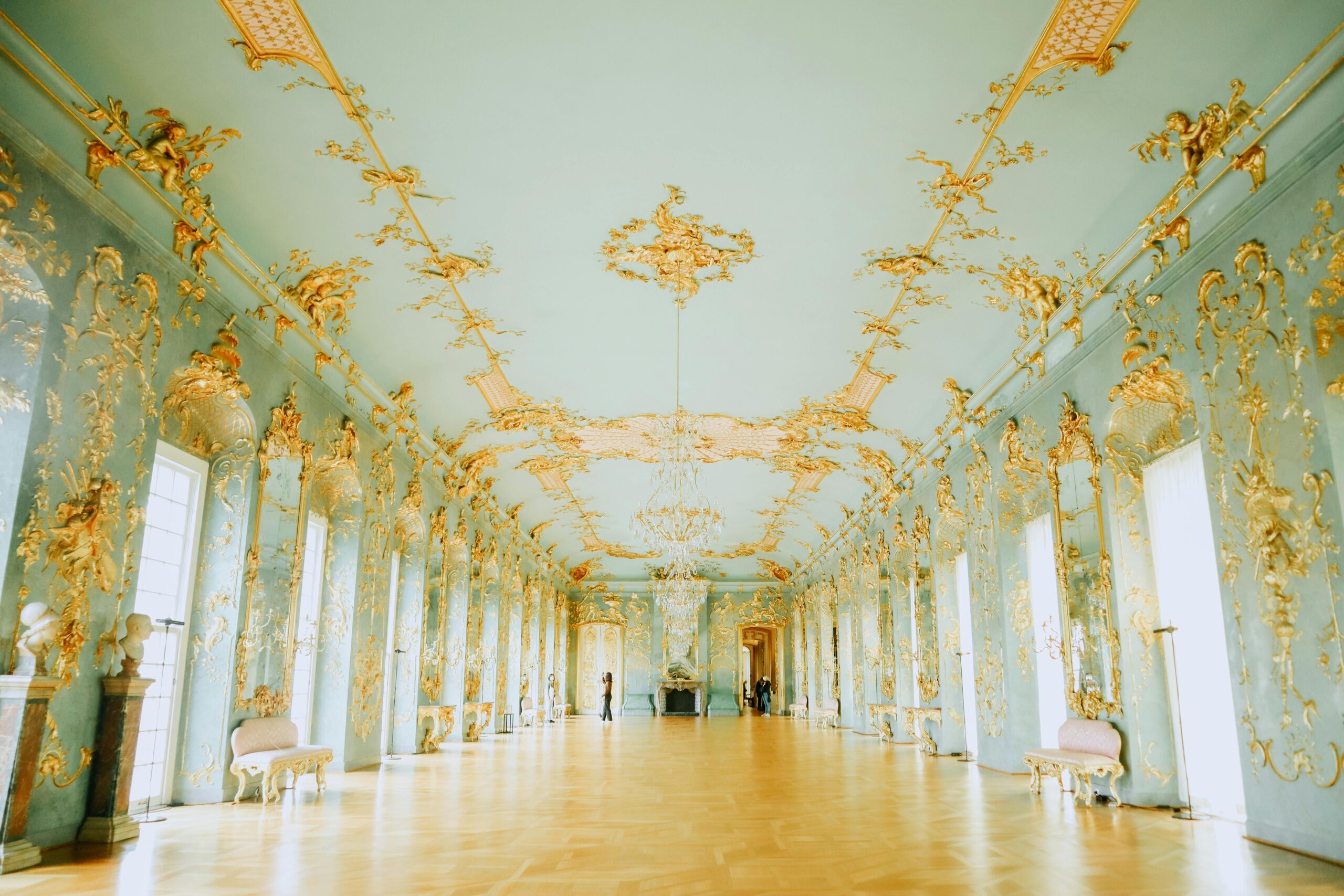 Luxurious Baroque-style room with intricate gold detailing and elegant chandeliers.