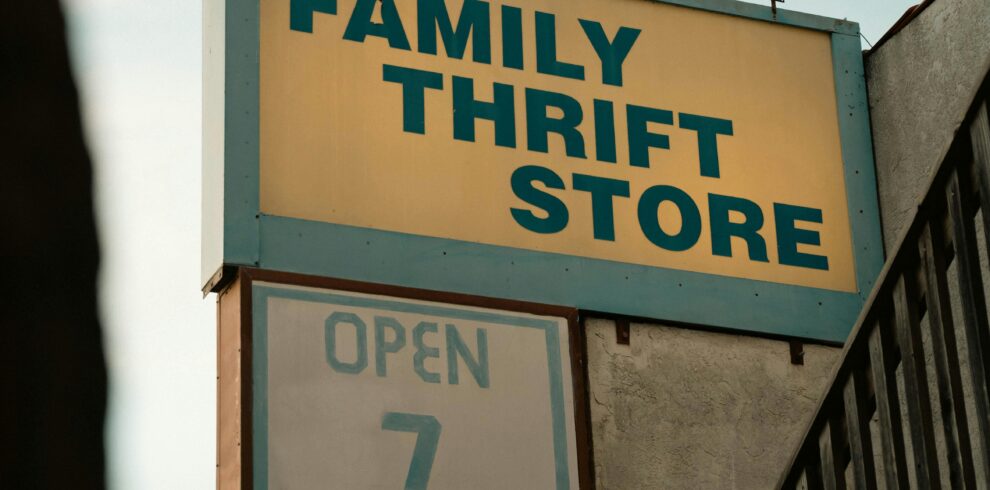 Retro-style sign for a family thrift store with stairs and wooden railing in view.