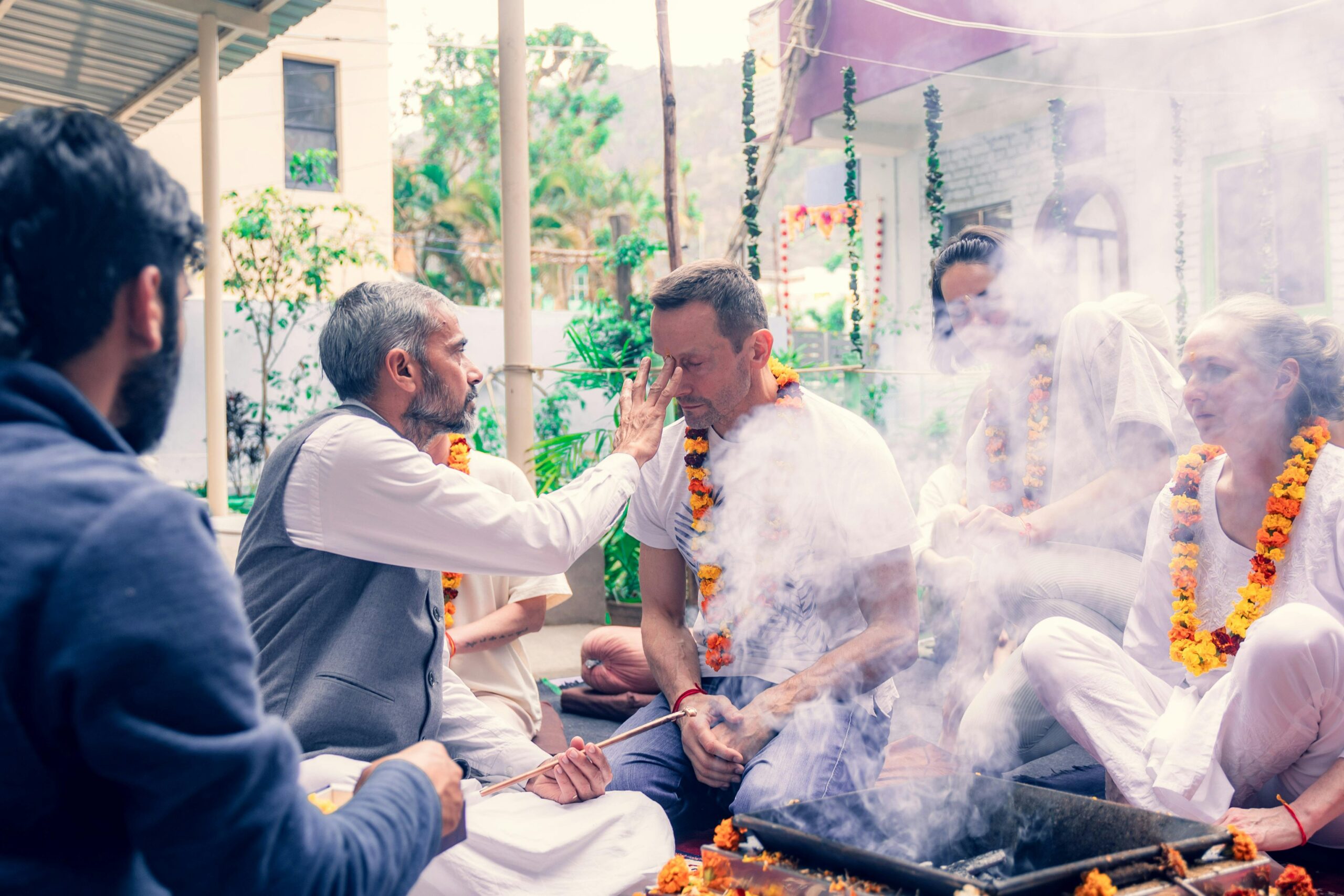 Meditative ceremony with garlanded individuals in Rishikesh, India performing traditional rituals.