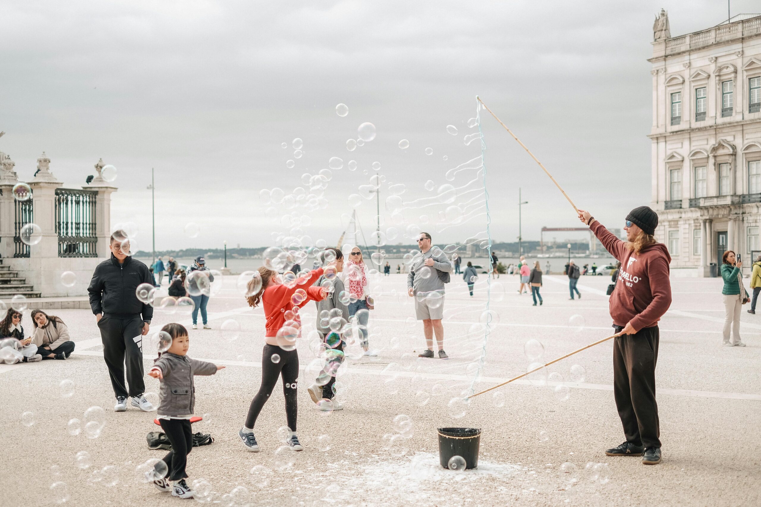 Children play with bubbles in a lively street performance outdoors.