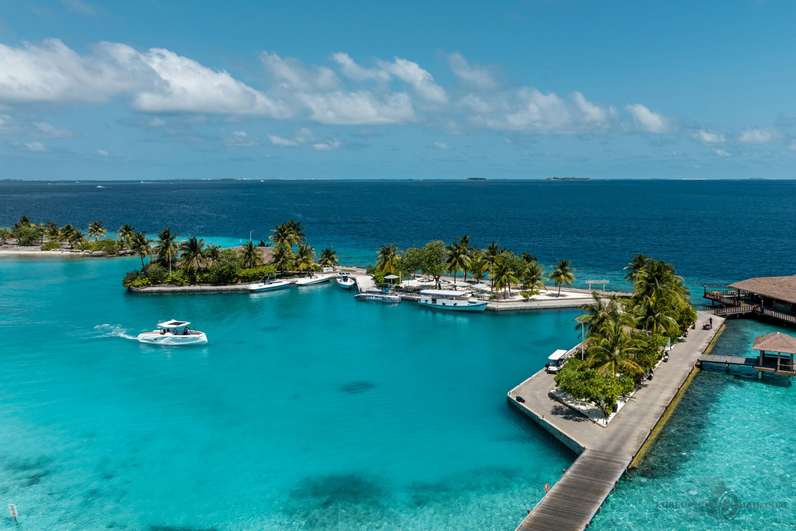 Captivating aerial view of a luxurious island resort in the Maldives showcasing turquoise waters and palm trees.