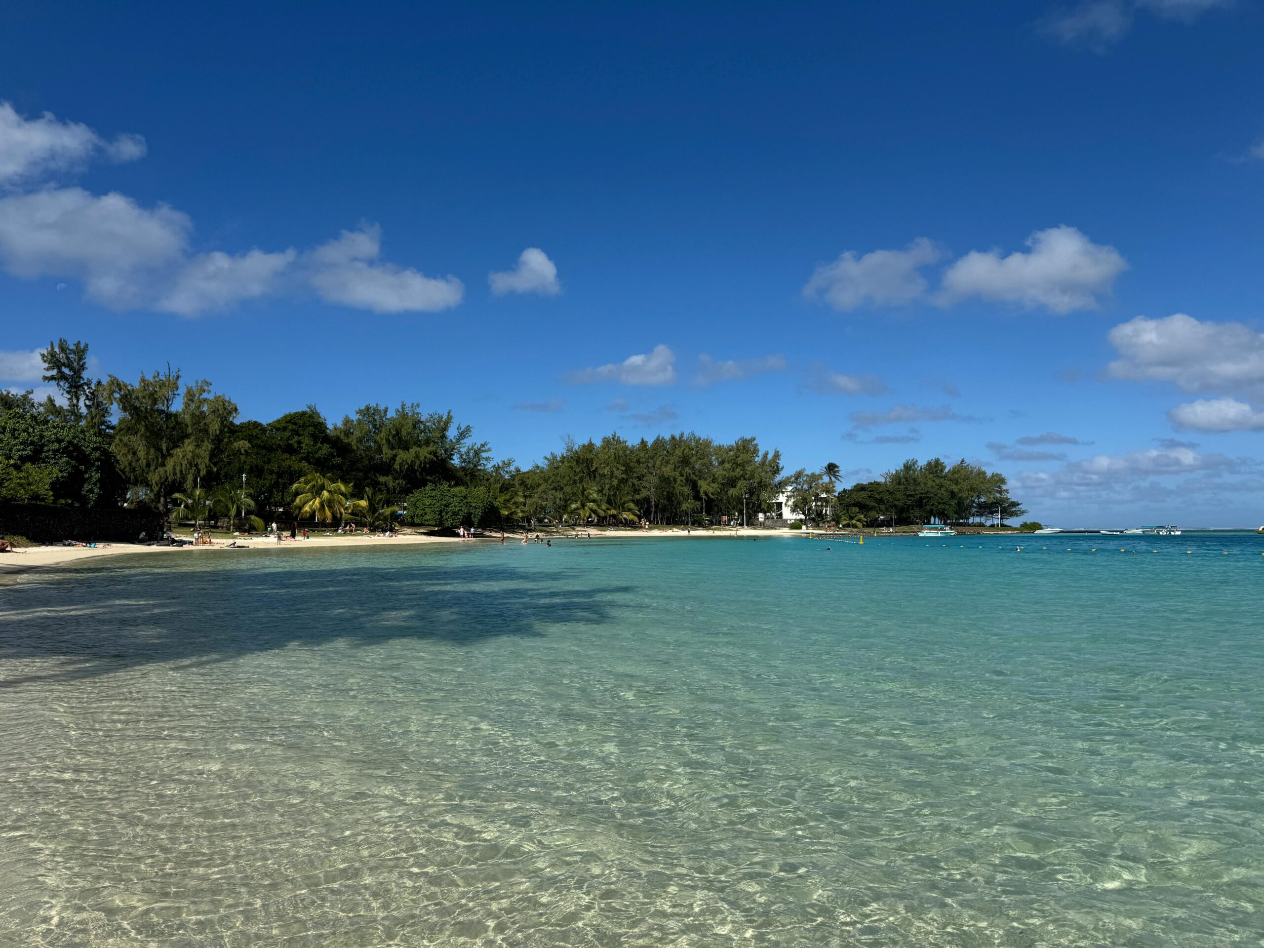 Pristine beach in Blue Bay, Mauritius with clear blue water and a sunny sky.