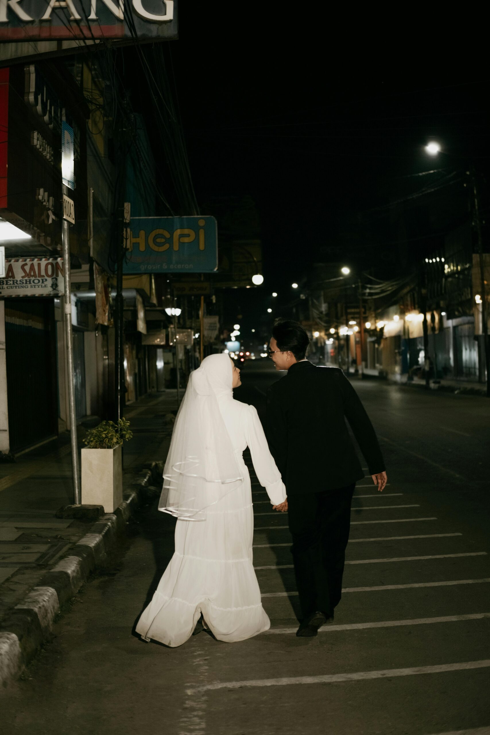 A Muslim couple enjoys a romantic walk in the city at night, capturing love and togetherness.