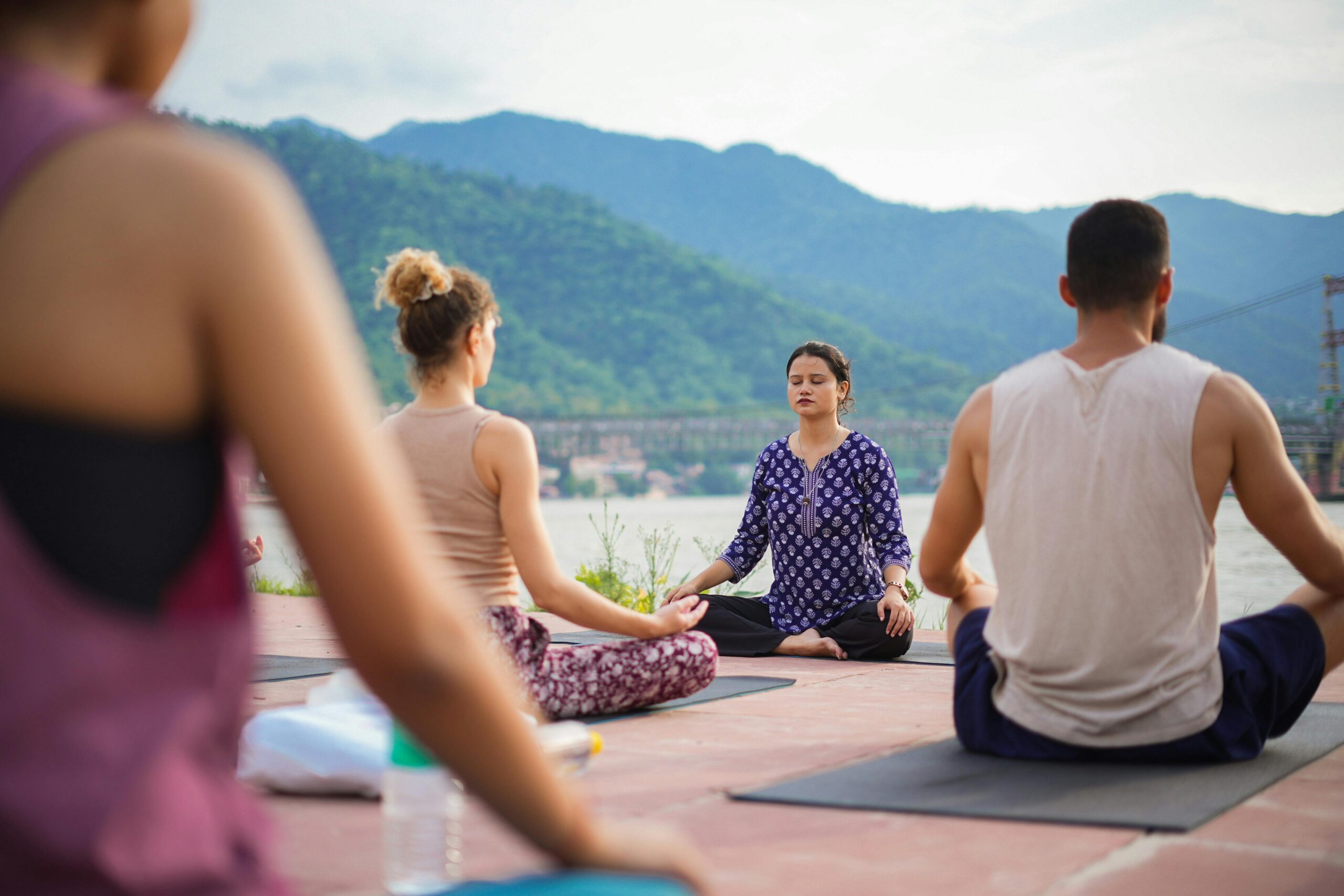 A group practicing yoga outdoors by the Ganges River in Rishikesh, India.