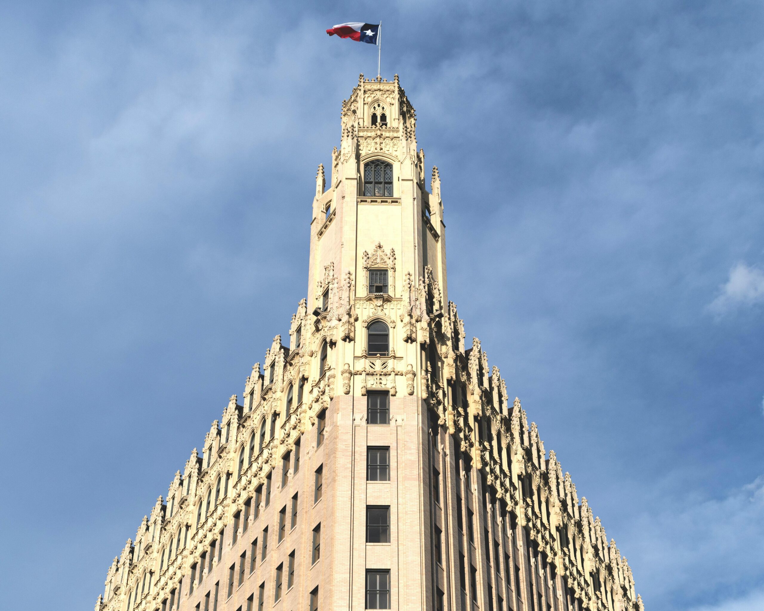 A historic skyscraper topped with a flag under a clear blue sky.
