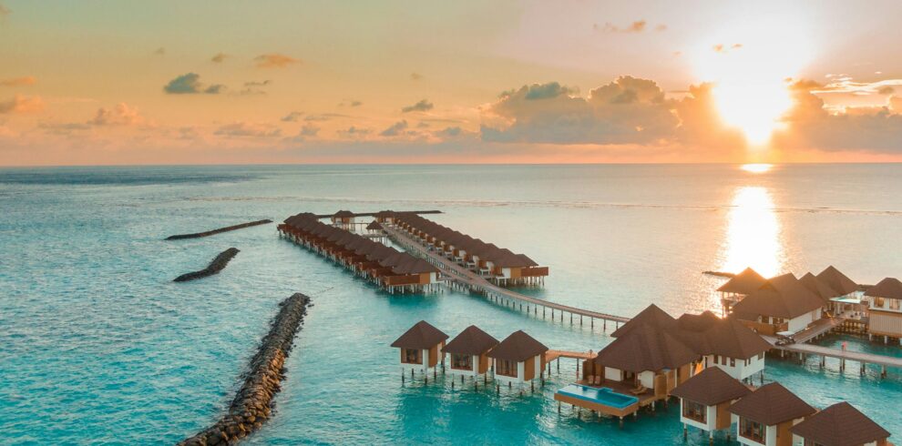 A breathtaking view of luxurious overwater villas in the Maldives at sunset.
