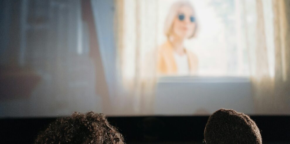 A couple enjoys a movie together in a cozy indoor cinema setting.