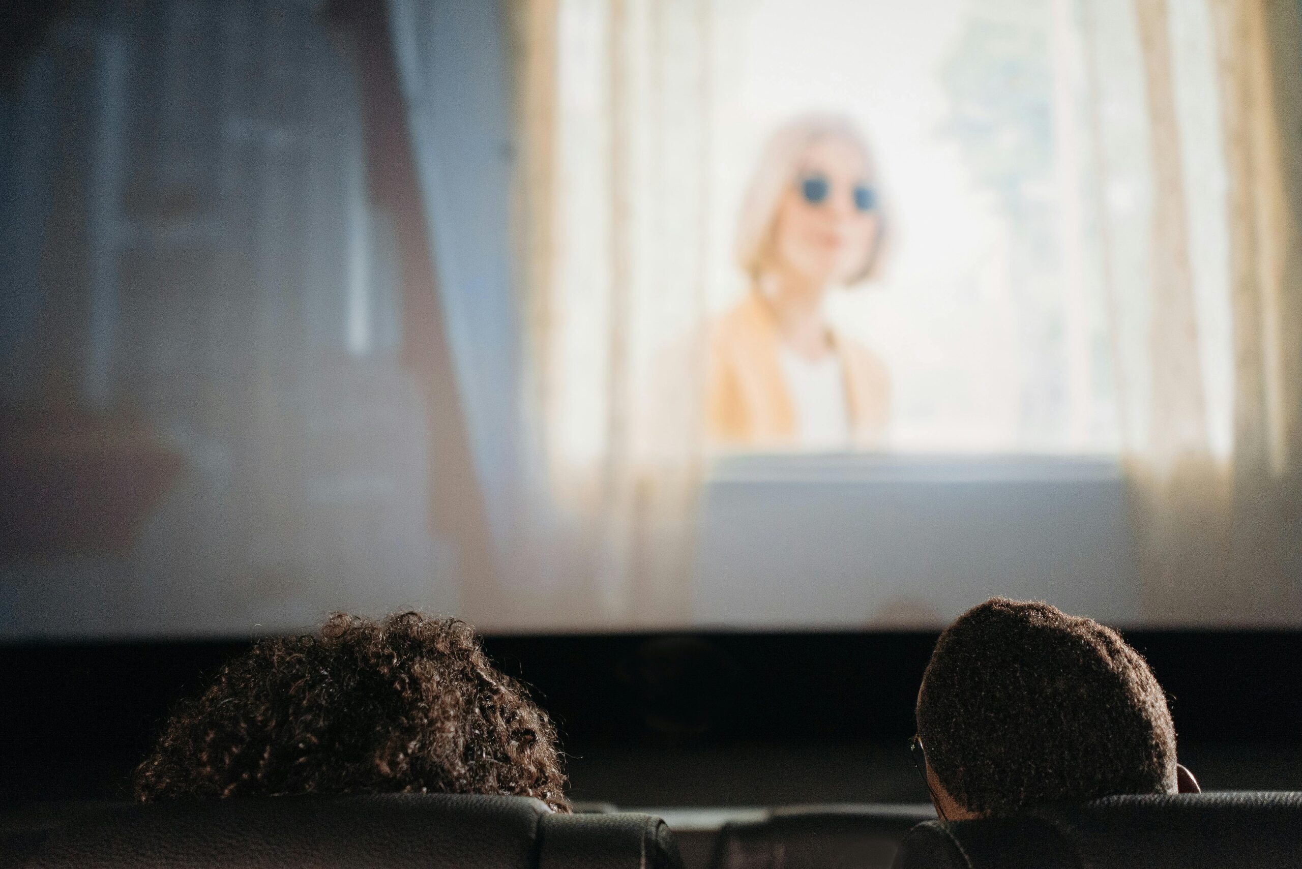 A couple enjoys a movie together in a cozy indoor cinema setting.
