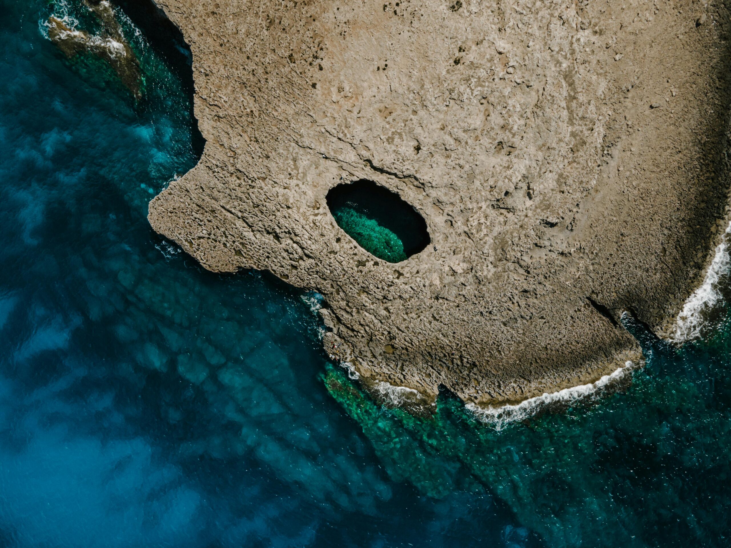 Stunning aerial shot of a rock formation with a natural pool in Il-Mellieħa, Malta.