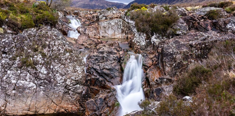 Breathtaking waterfall surrounded by rugged rocks in the Scottish Highlands, showcasing natural beauty.