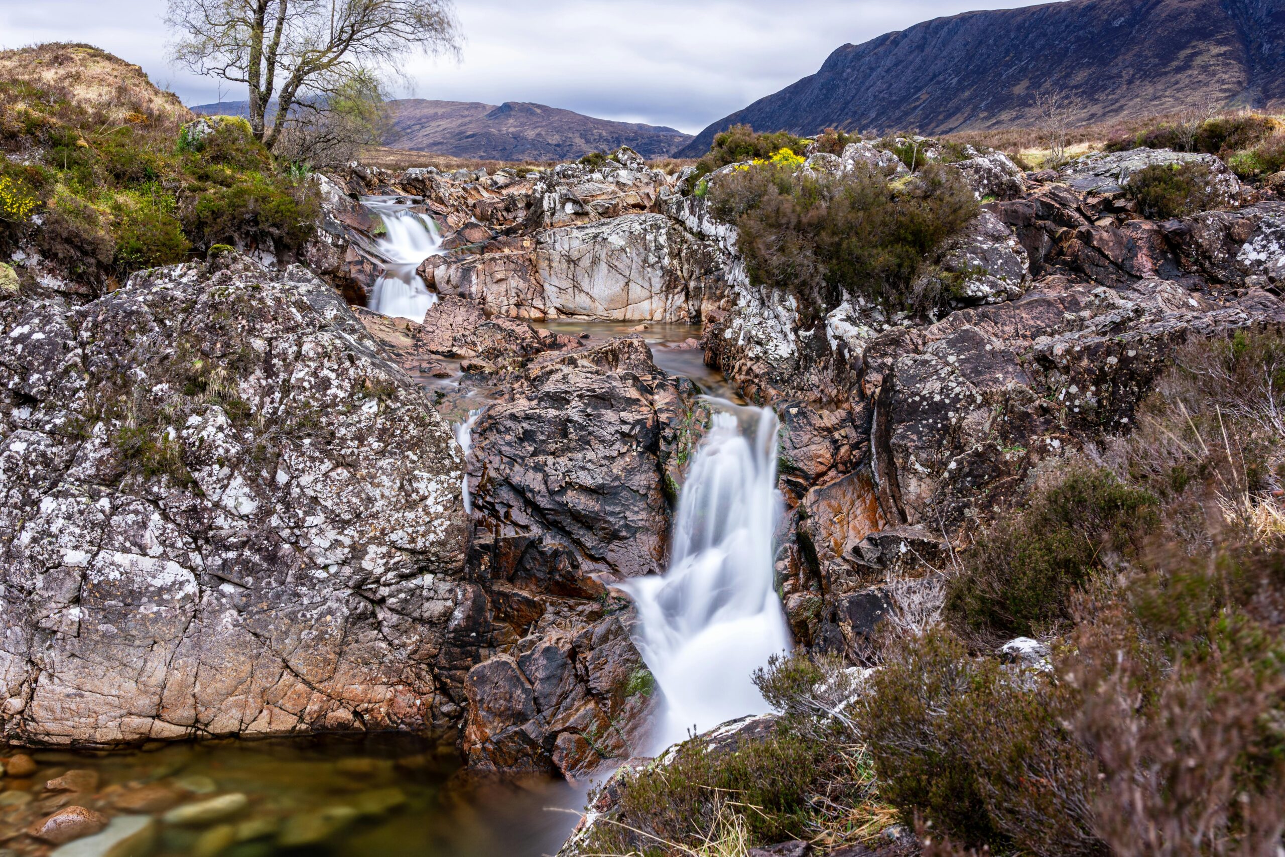 Breathtaking waterfall surrounded by rugged rocks in the Scottish Highlands, showcasing natural beauty.
