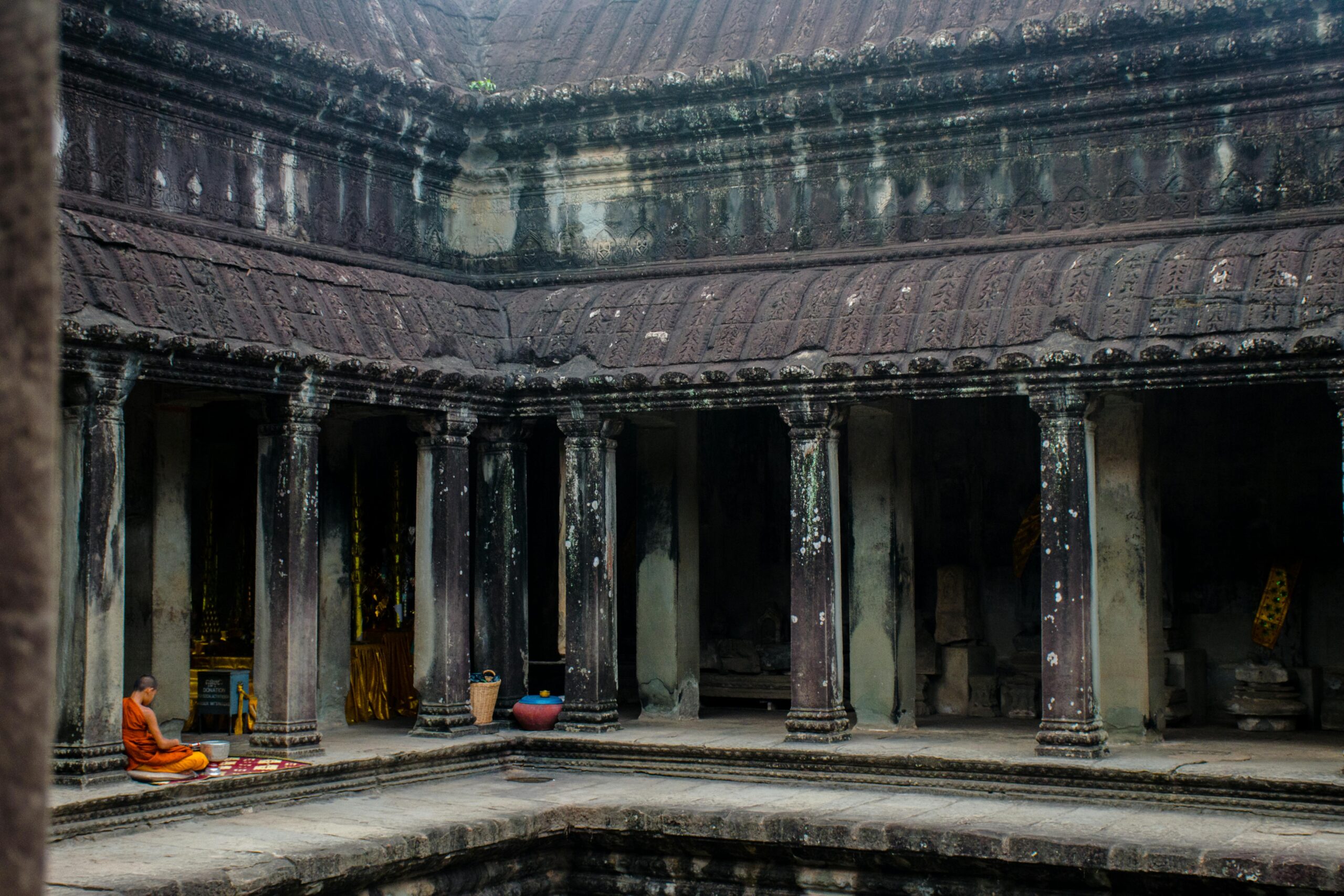 A Buddhist monk meditates peacefully in the historic Angkor Wat temple, Cambodia.