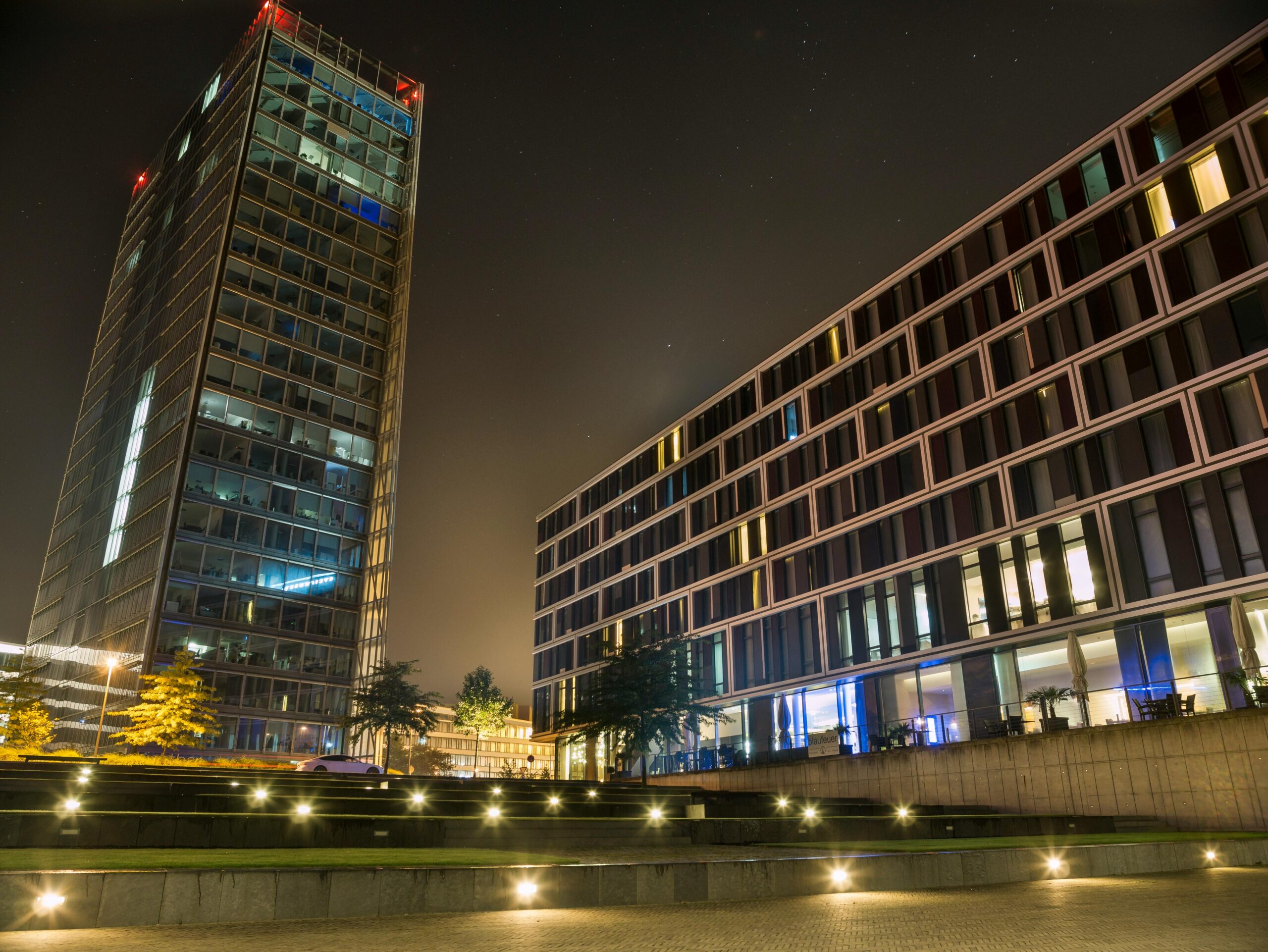 A stunning view of modern buildings illuminated at night with a starry sky backdrop.