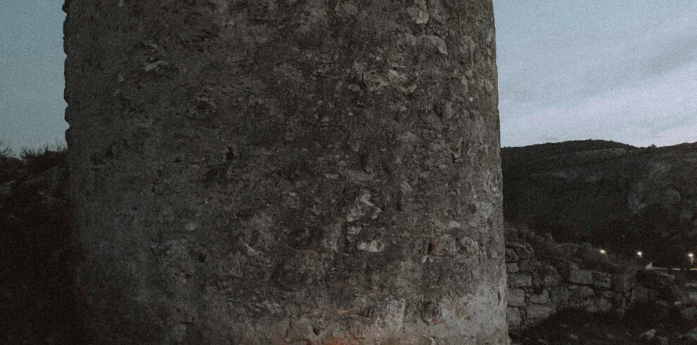 Couple embraces by candlelight near ancient tower, capturing timeless romance.