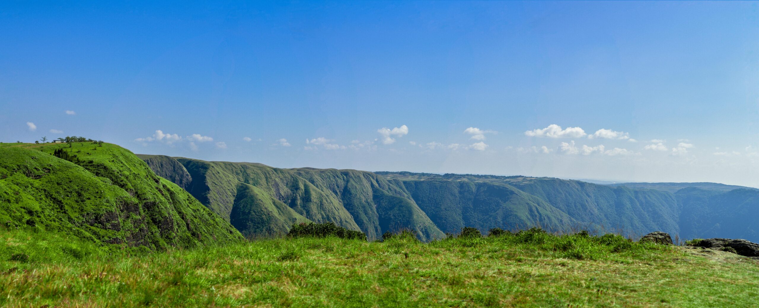 Stunning panoramic view of Meghalaya's lush green hill ranges under a clear blue sky.