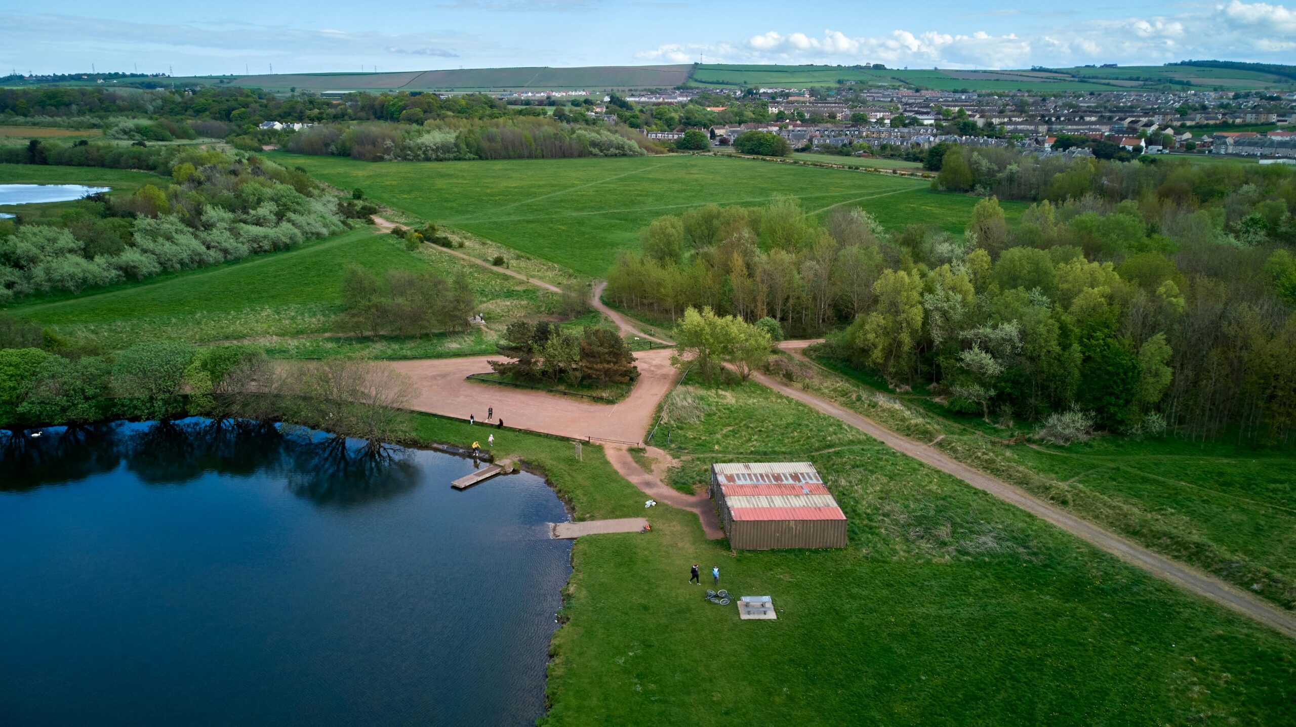 Aerial view of East Lothian countryside featuring a serene lake and lush fields.