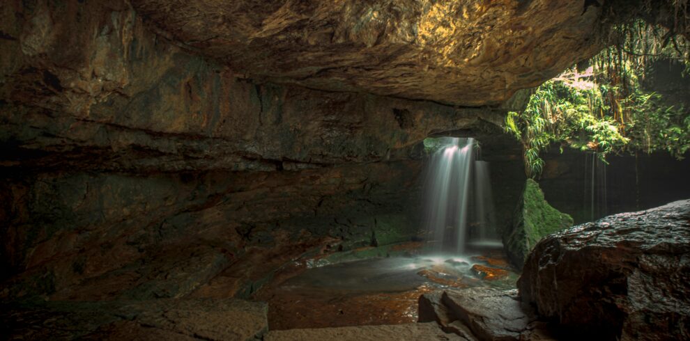 Serene waterfall cascading inside a natural cave in ML, India, offering a tranquil environment.