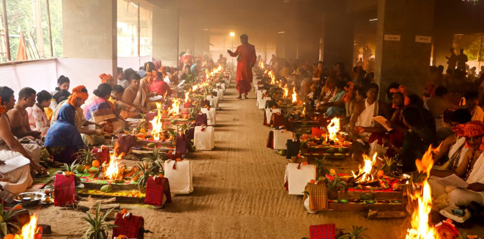 A vibrant and colorful Hindu ritual with participants in traditional attire and ceremonial fires in Dhaka.