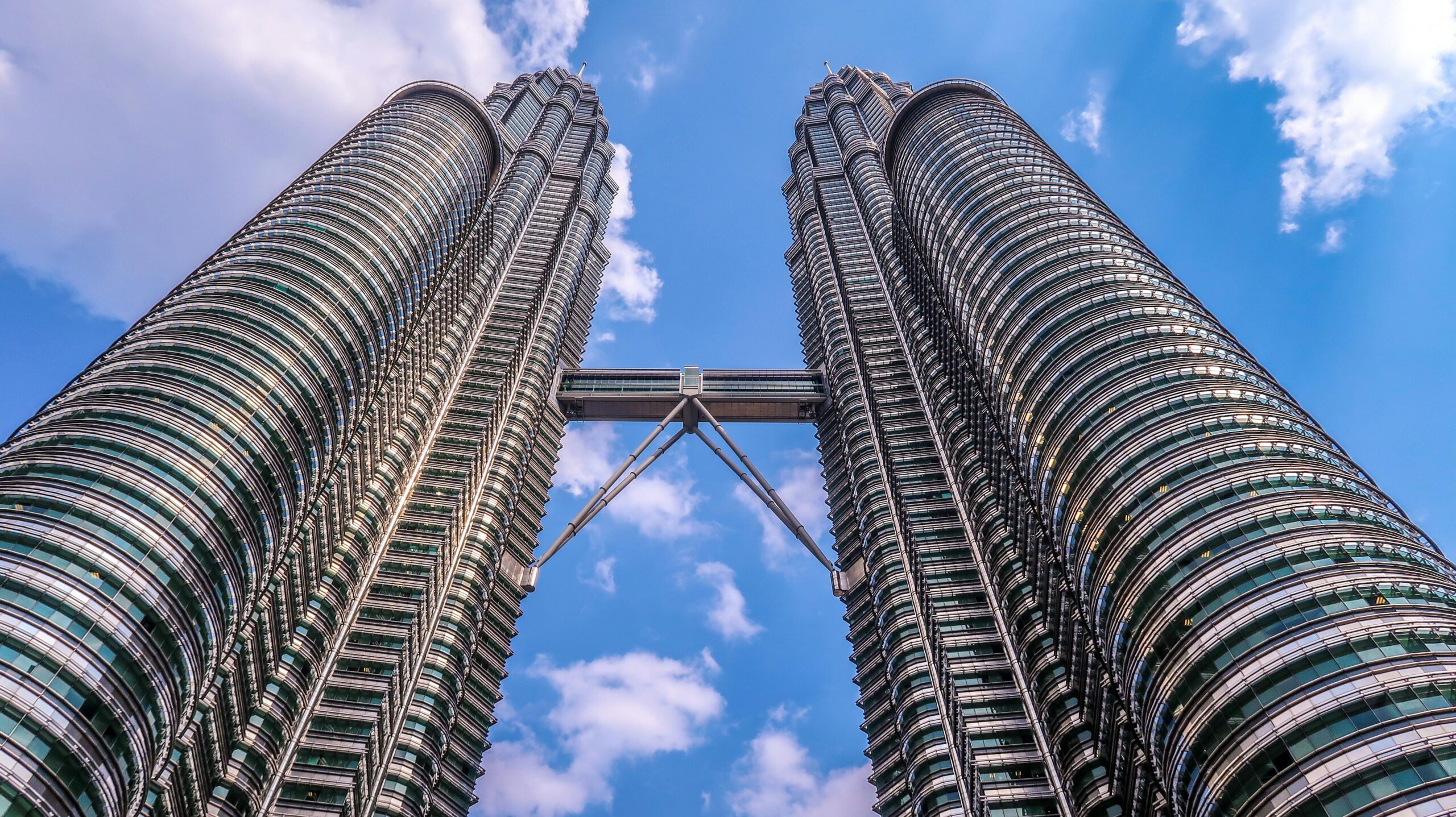 Low angle view of the iconic Petronas Twin Towers in Kuala Lumpur, Malaysia, against a clear blue sky.