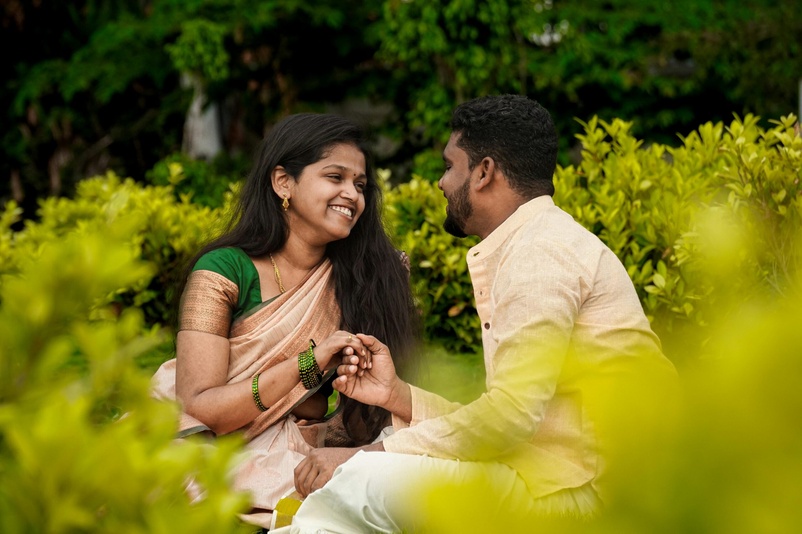 Couple sharing a moment of love and happiness in a vibrant green park, dressed in traditional attire.
