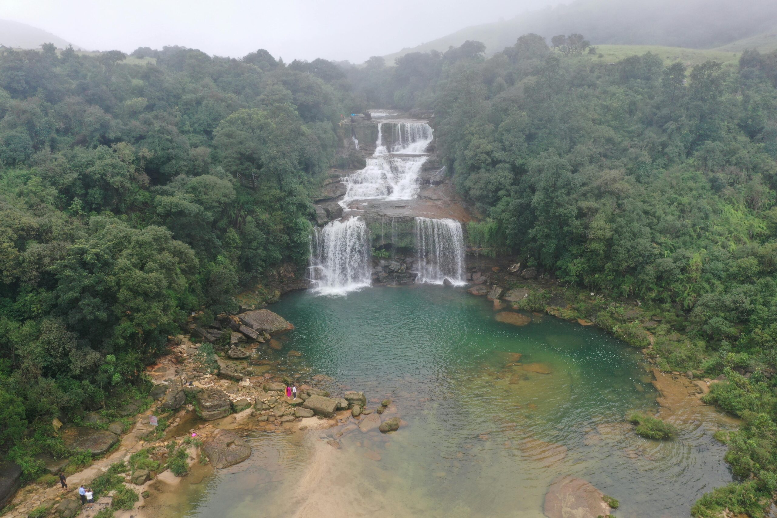 Stunning aerial view of a waterfall surrounded by dense jungle in Meghalaya, India.