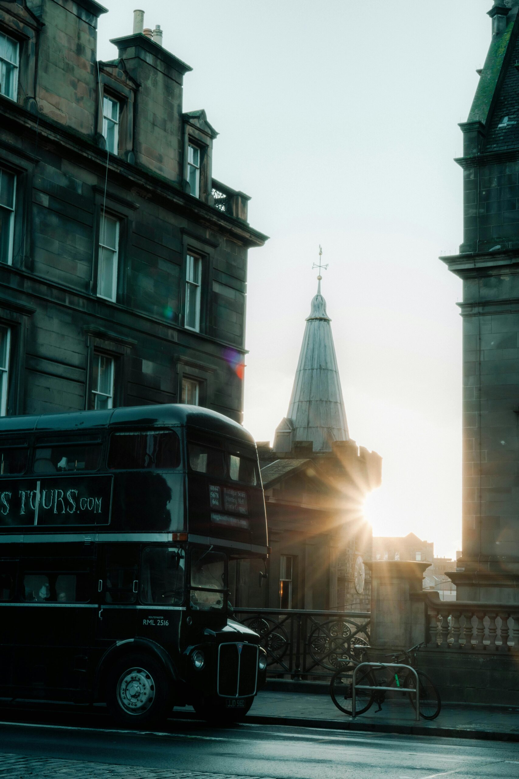 A scenic sunset view highlighting historic architecture and a classic double-decker bus in Scotland.