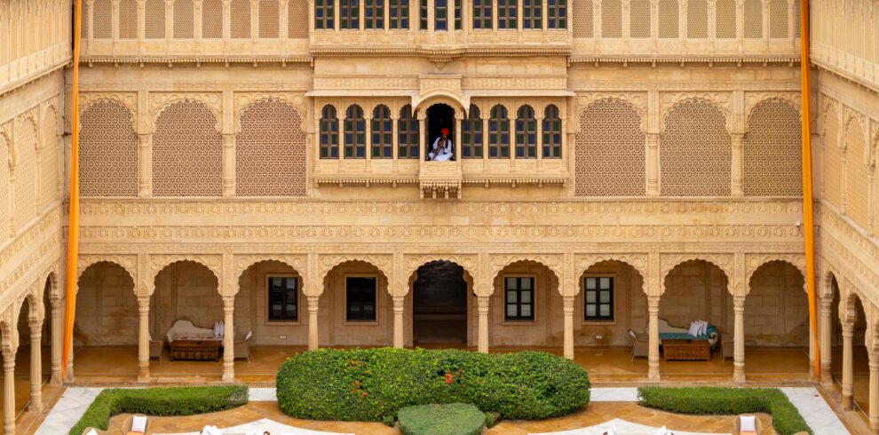 Luxurious sandstone courtyard with intricate carvings in Jaisalmer's heritage Suryagarh Palace.