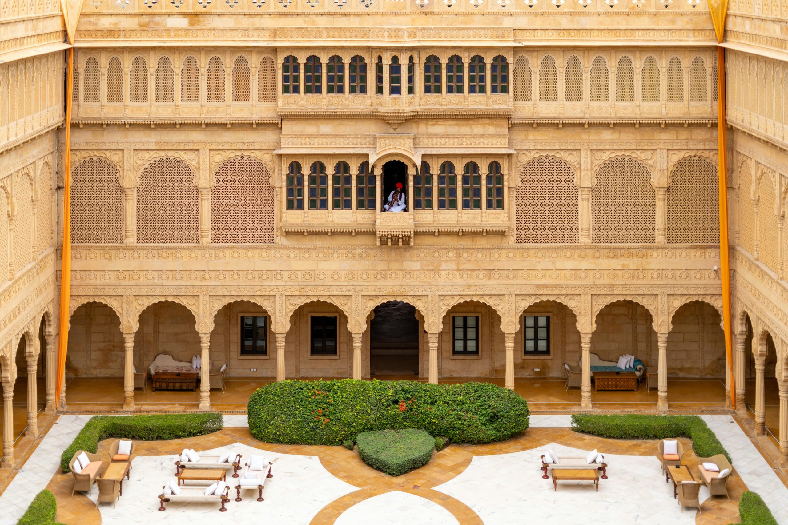 Luxurious sandstone courtyard with intricate carvings in Jaisalmer's heritage Suryagarh Palace.